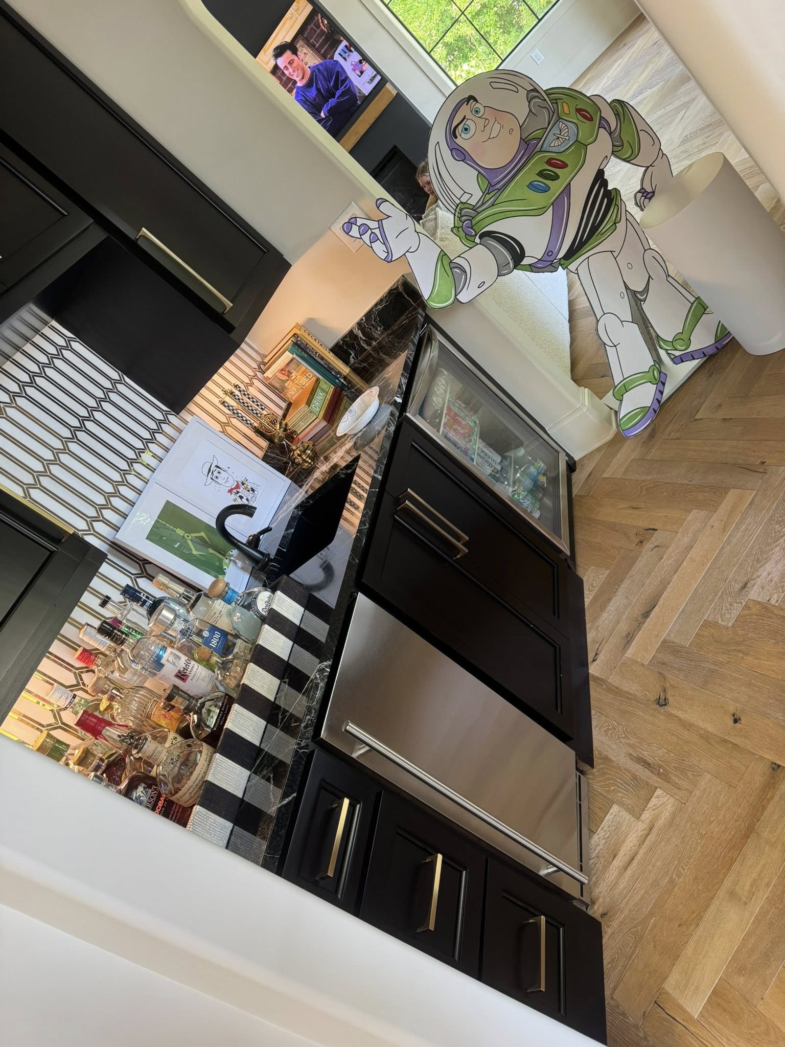A home bar area featuring black cabinetry, a built-in refrigerator, and a Buzz Lightyear cardboard cutout.