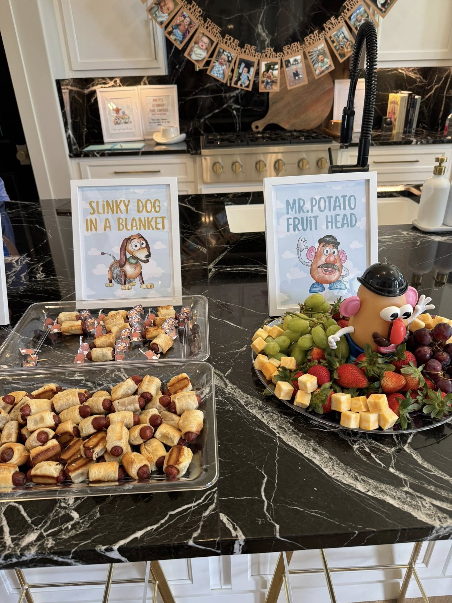 Toy Story inspired party food display featuring Slinky Dog in a Blanket and a Mr. Potato Head fruit platter.