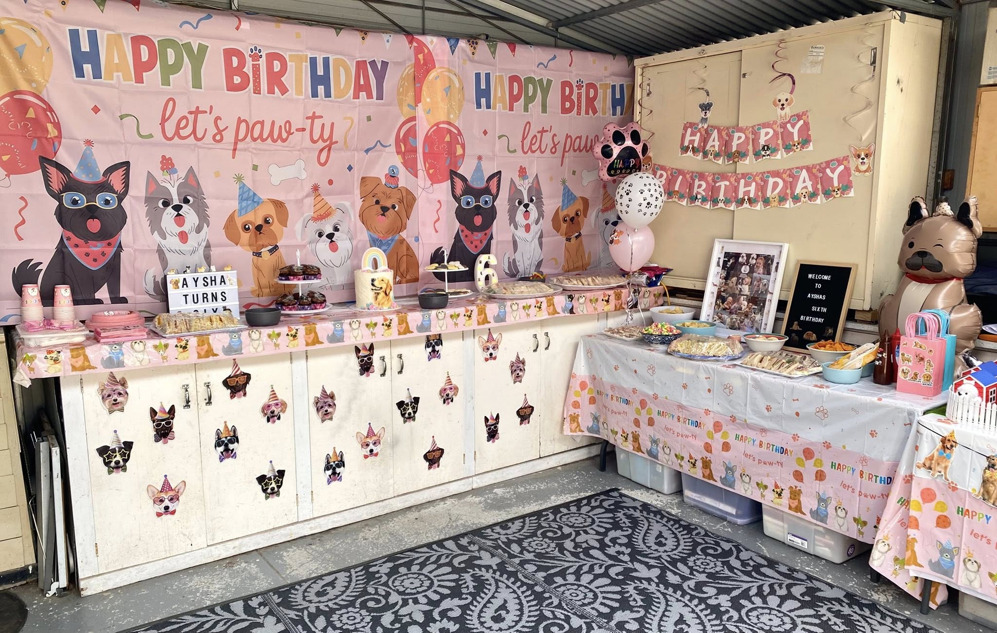 Puppy-themed birthday party decorations featuring paw print banners, puppy wall backdrops, and table settings.