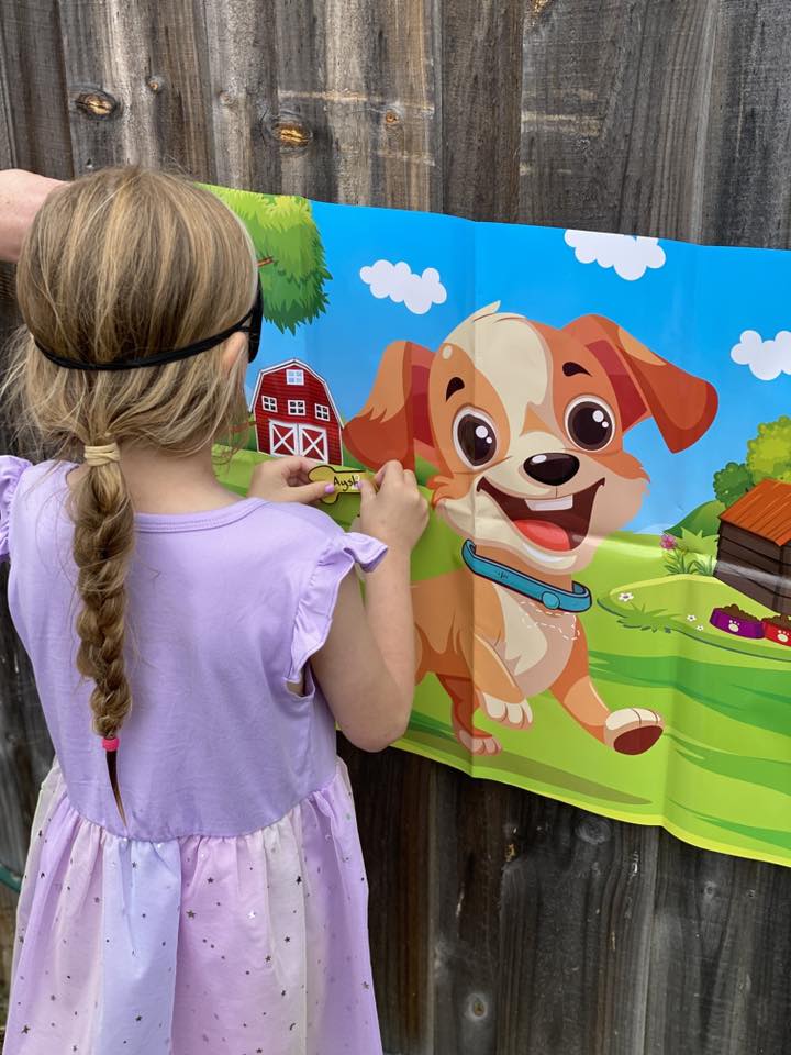 Girl wearing a blindfold playing a Pin the Bone on the Puppy party game