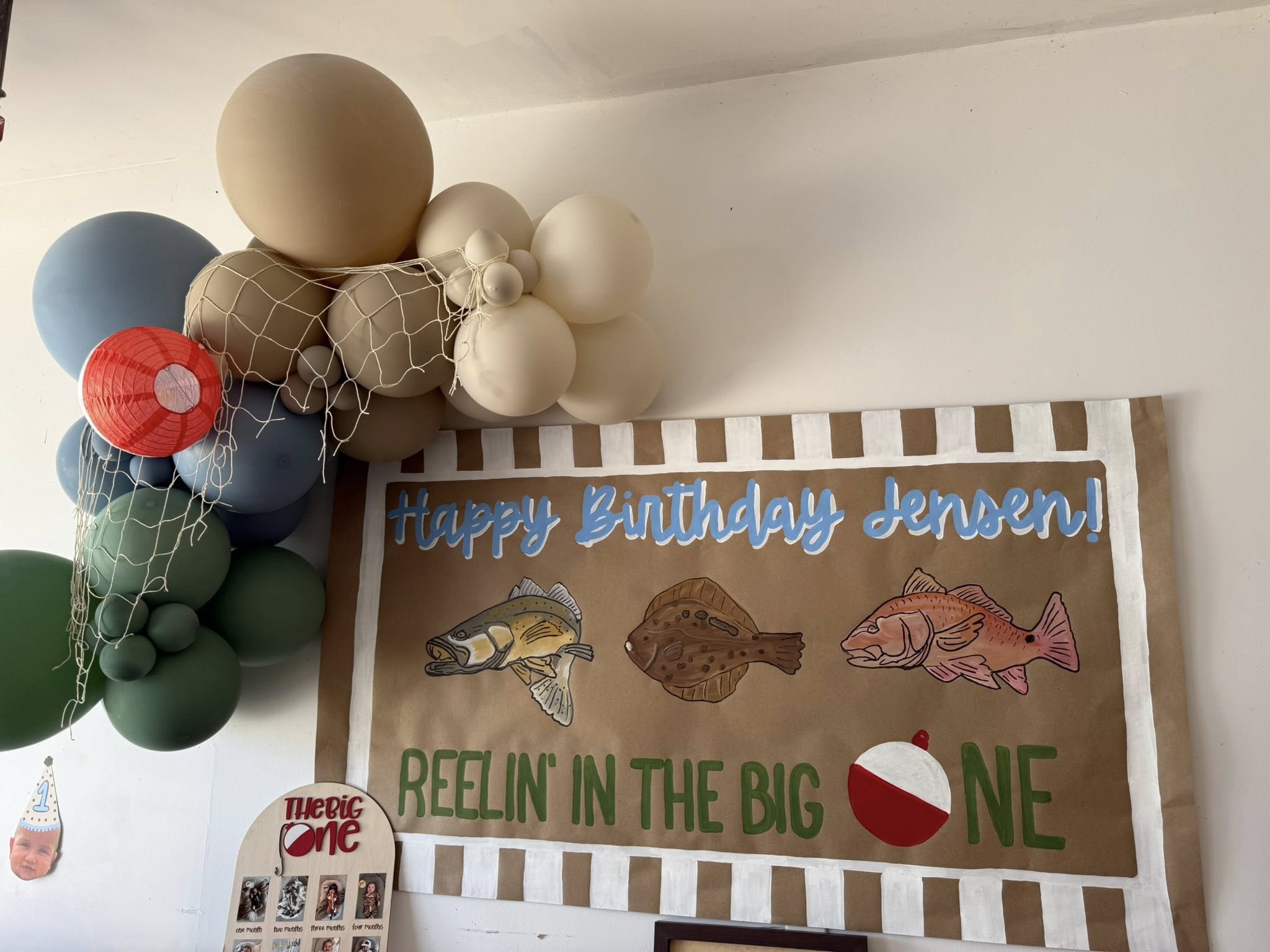Happy Birthday Jensen fishing-themed banner with neutral-toned balloon arch and decorative fishing net.