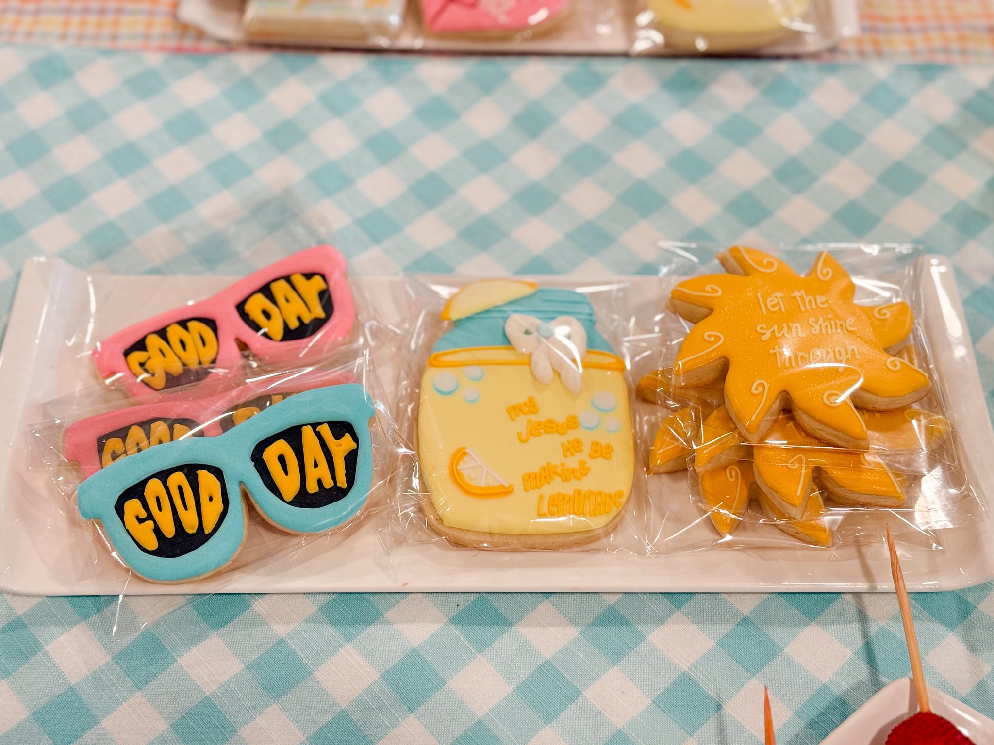 Decorated sugar cookies in shapes of sunglasses, lemonade, and a sun with inspirational text on a white platter.