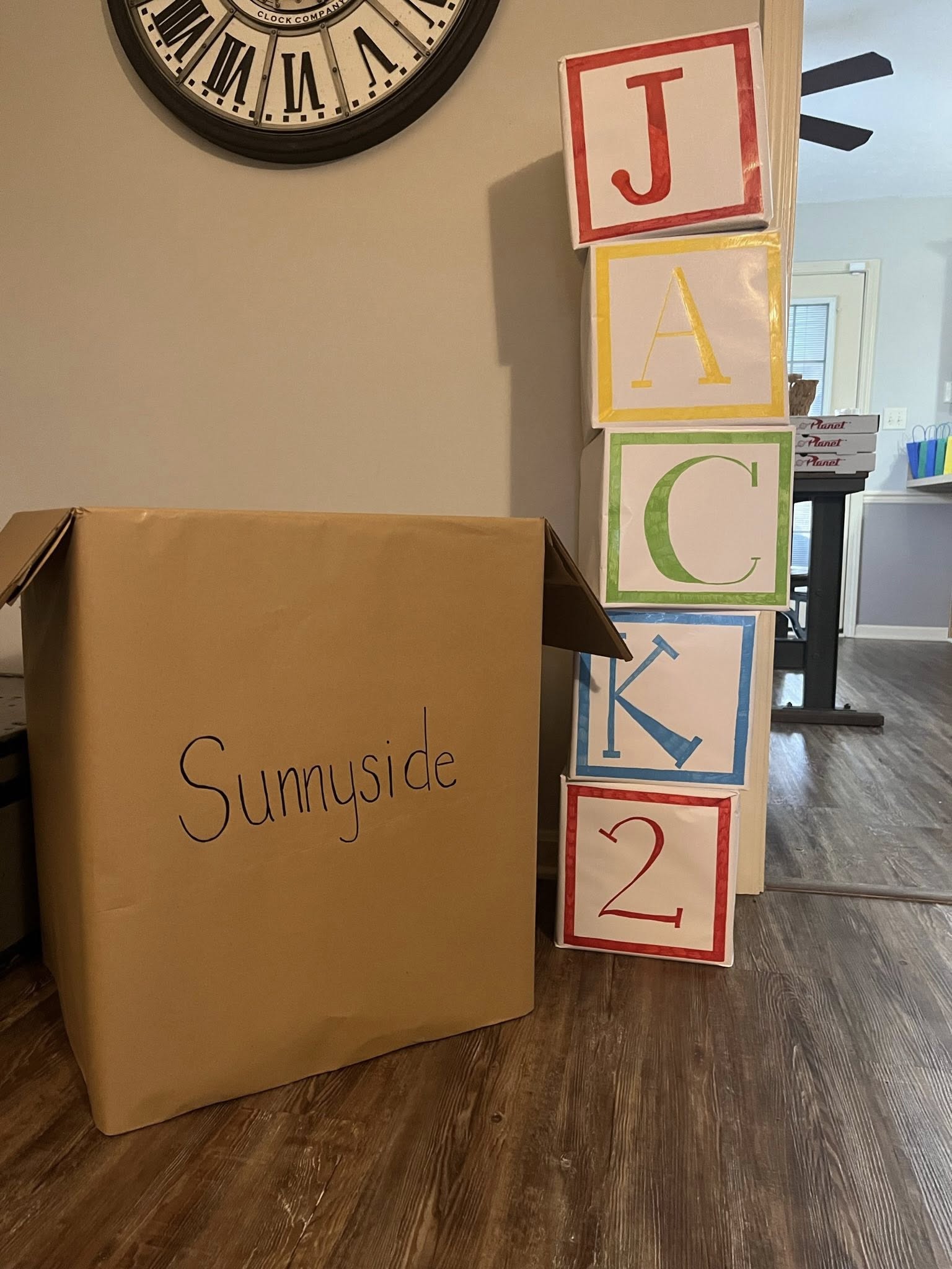 A cardboard box labeled Sunnyside next to a stack of blocks spelling Jack 2 for a party decoration.