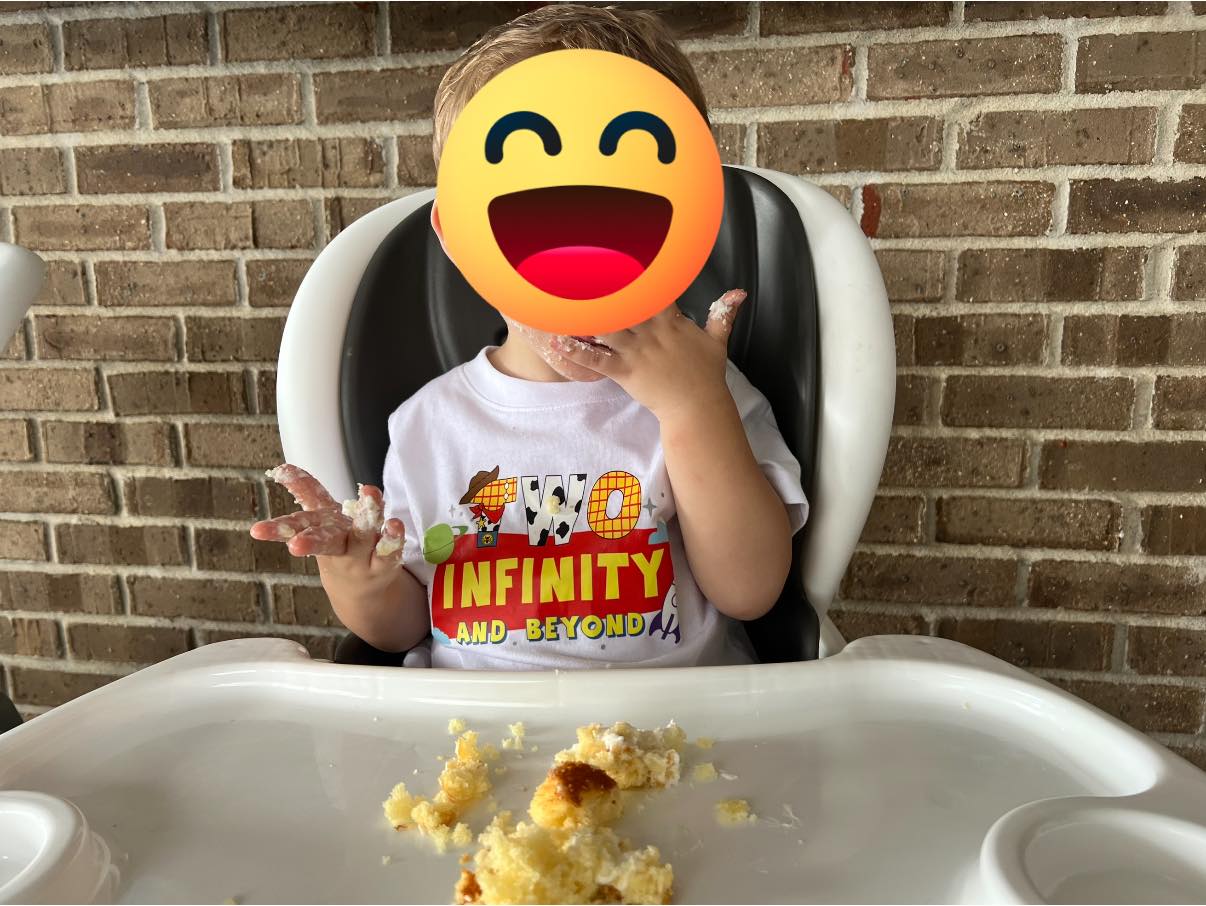 Toddler in a Toy Story Two Infinity and Beyond t-shirt eating cake in a high chair