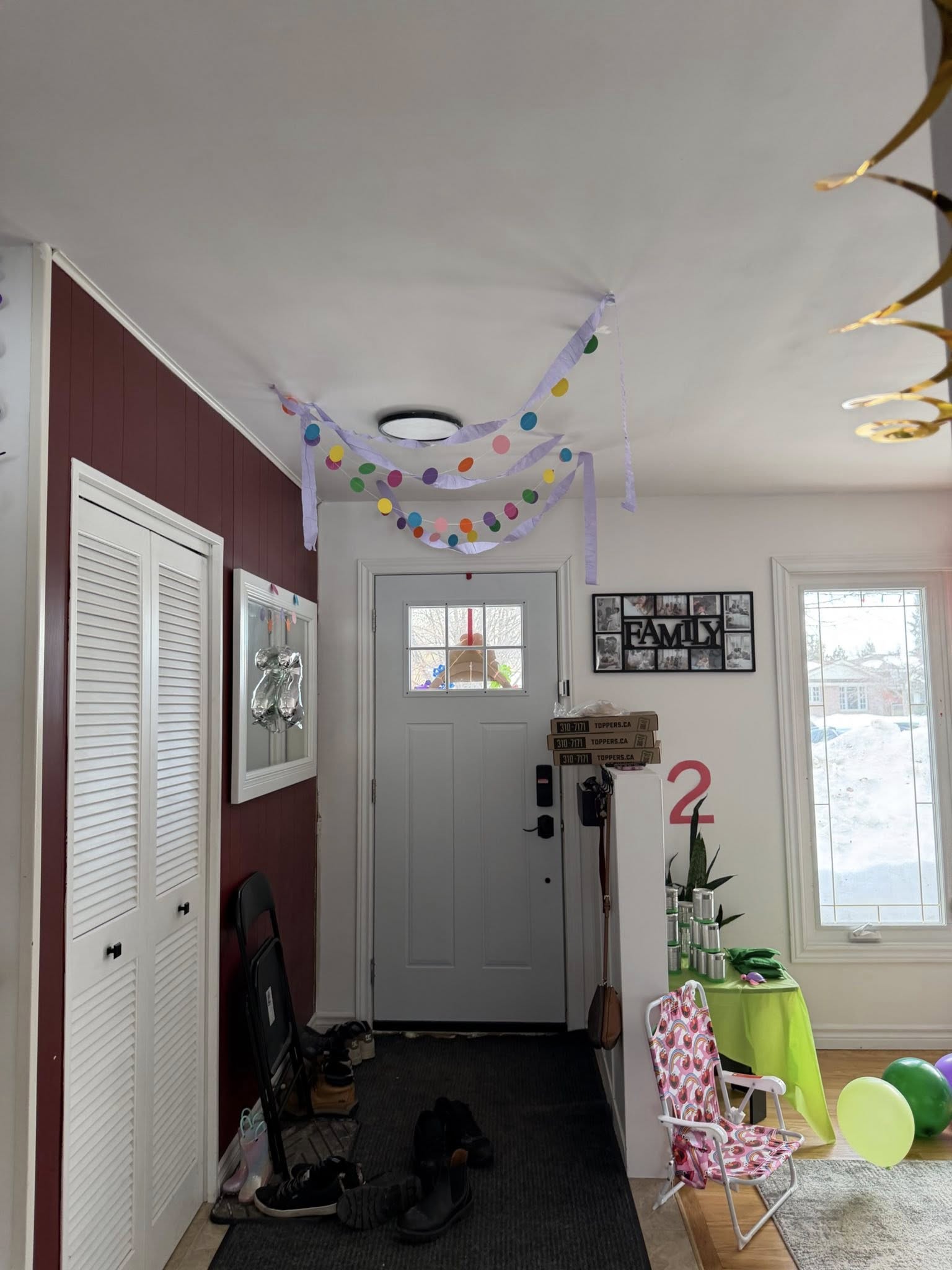 Entryway decorated for a second birthday party with streamers, a number two sign, and balloons.