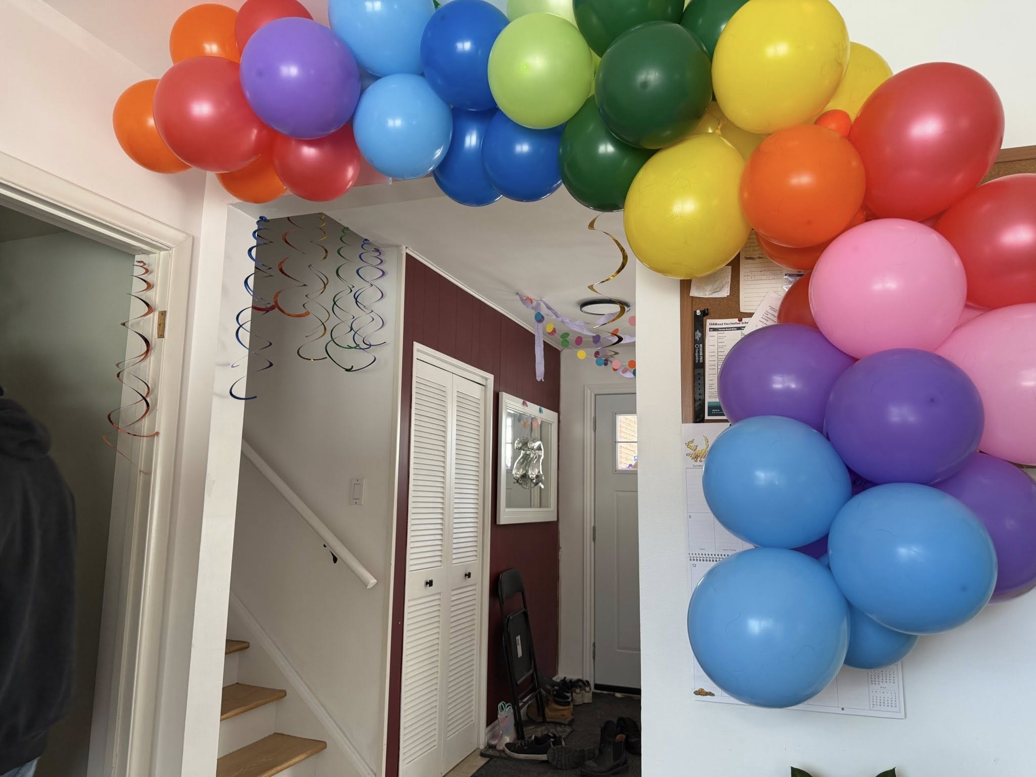 Rainbow colored balloon arch framing an indoor doorway
