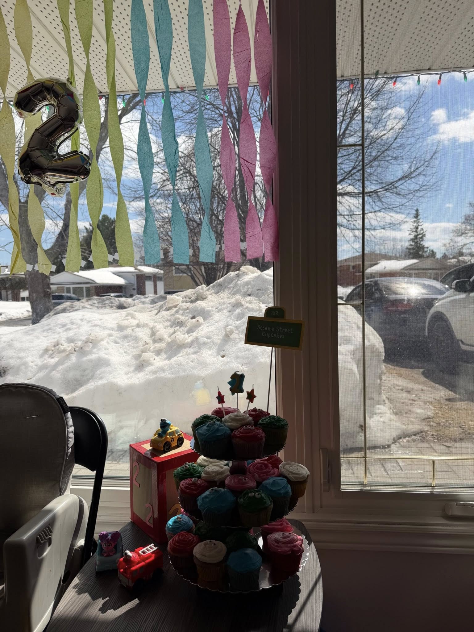 Tiered stand filled with Sesame Street decorated cupcakes for a second birthday celebration.