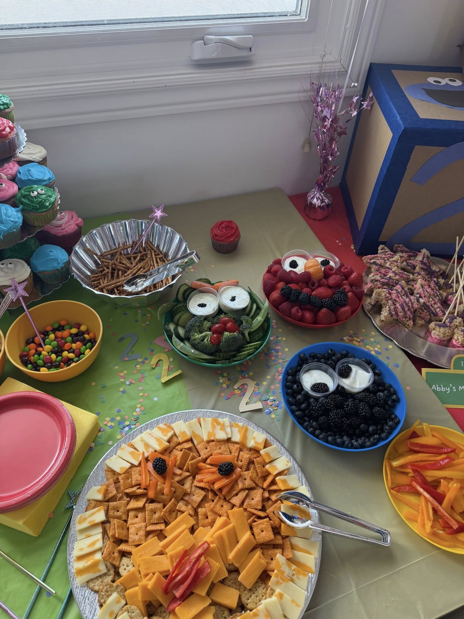 Sesame Street theme birthday party food spread featuring snacks arranged like Elmo and Cookie Monster characters.