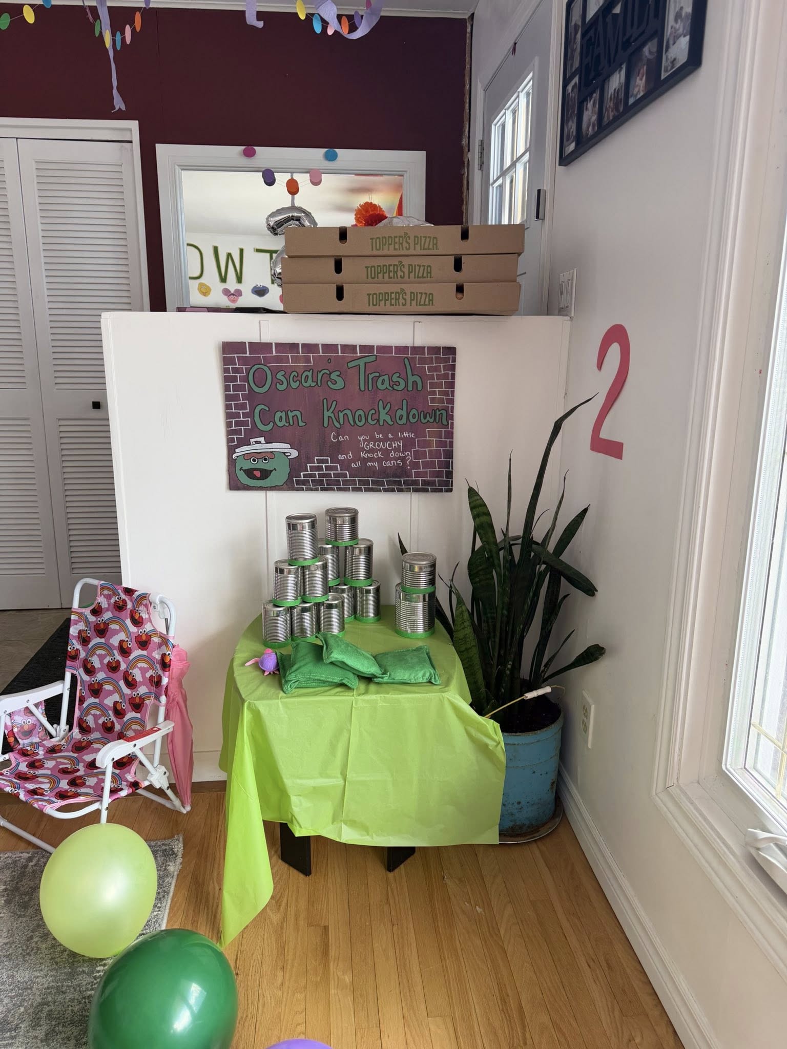 Oscar's Trash Can Knockdown game setup with stacked metal cans and green bean bags on a table at a party.