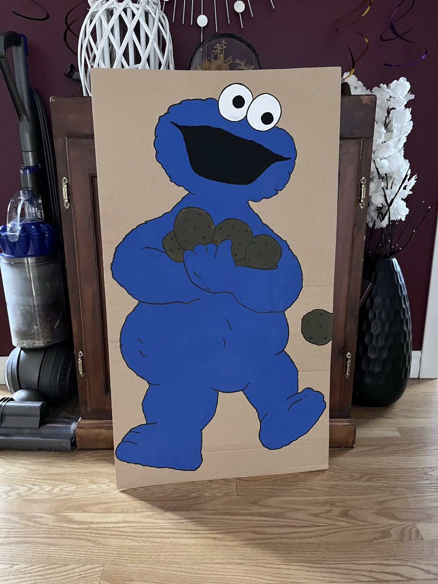 Cardboard cutout of Cookie Monster holding several chocolate chip cookies for a party game.