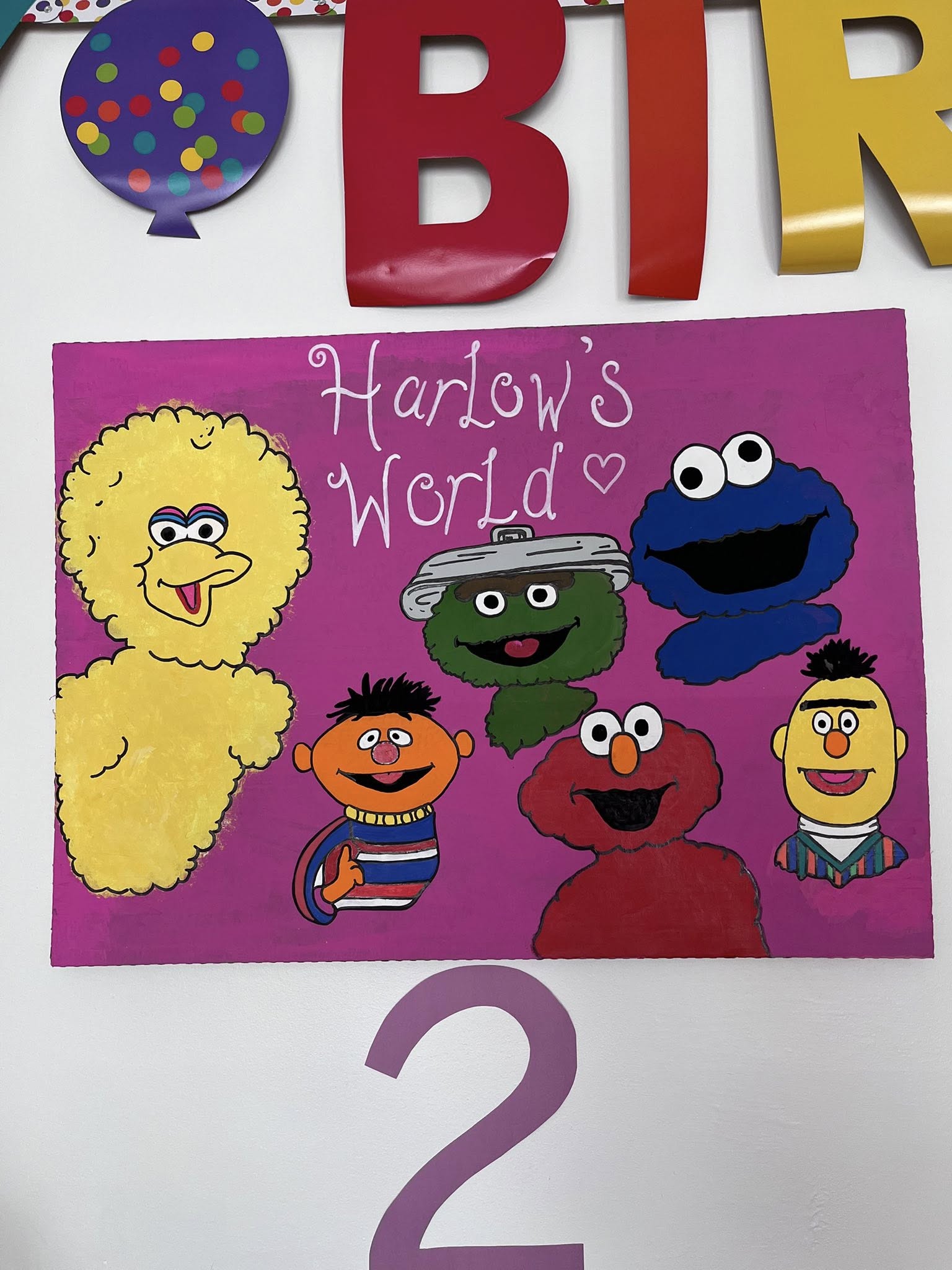 Hand-painted sign on pink background featuring Big Bird, Ernie, Oscar the Grouch, Cookie Monster, Elmo, and Bert with the text Harlow's World.