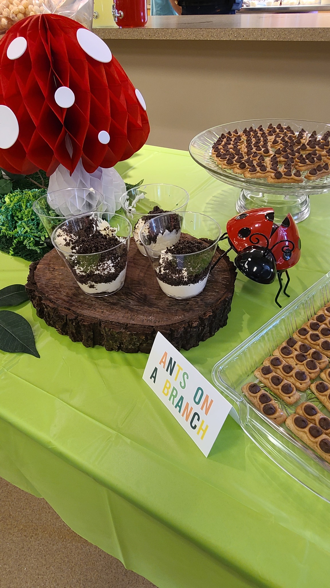 Table display with Ants on a Branch sign, mushroom decor, and cups of pudding with cookie crumbles.