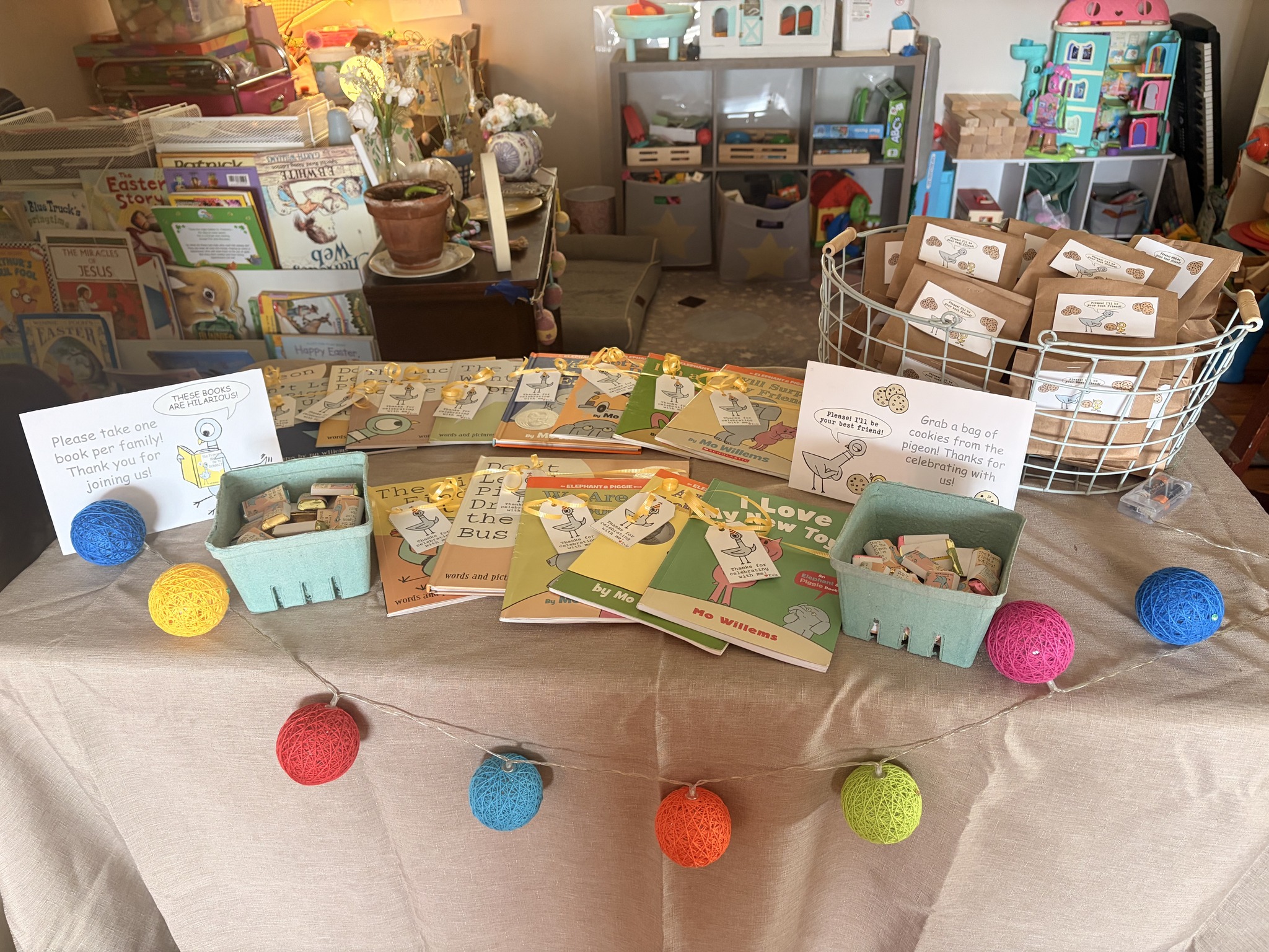 Party favor table with Mo Willems Elephant and Piggie books, cookie bags, and signs for guests.