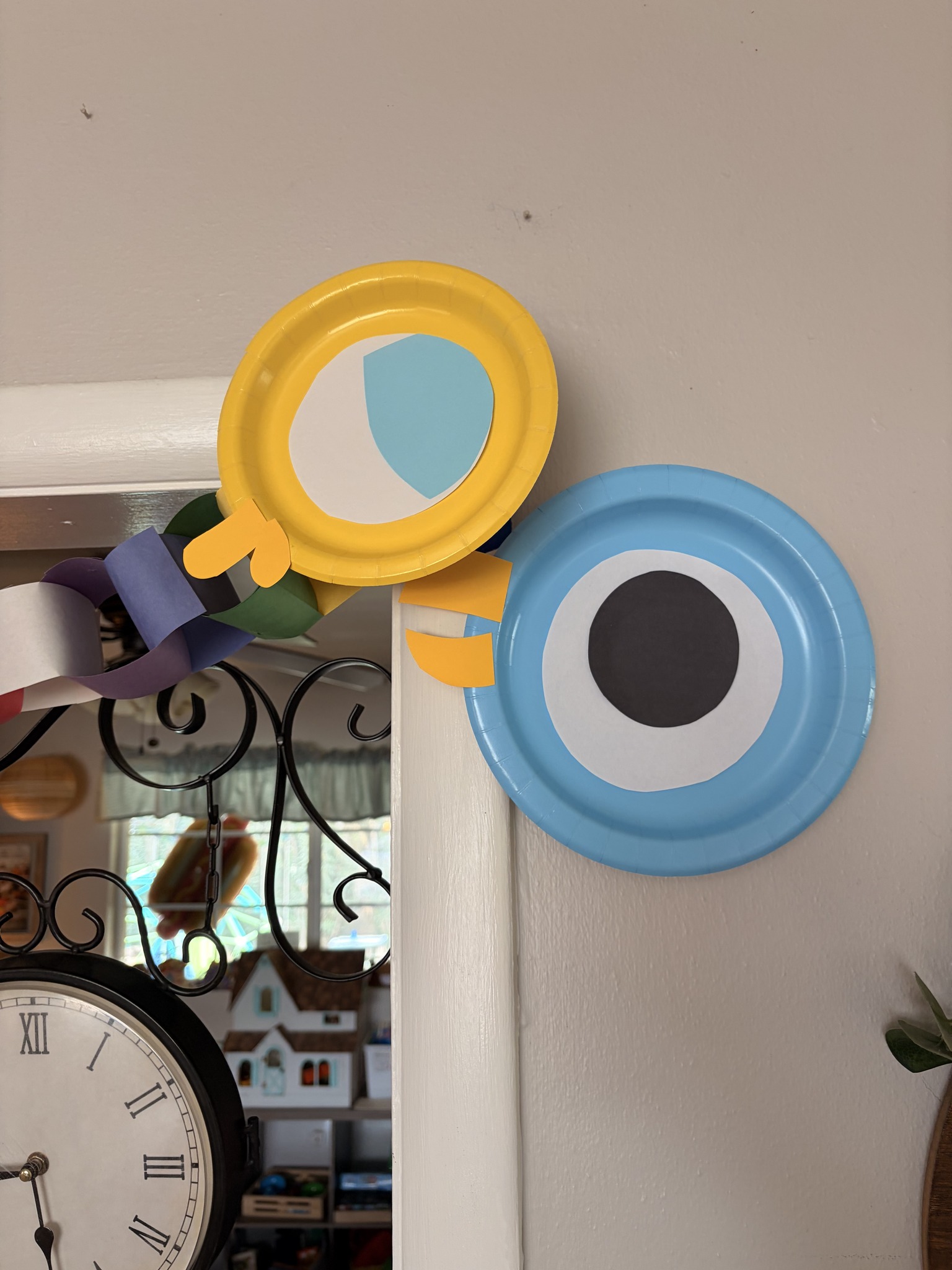 Handmade paper plate character decorations in yellow and blue hanging on a doorway