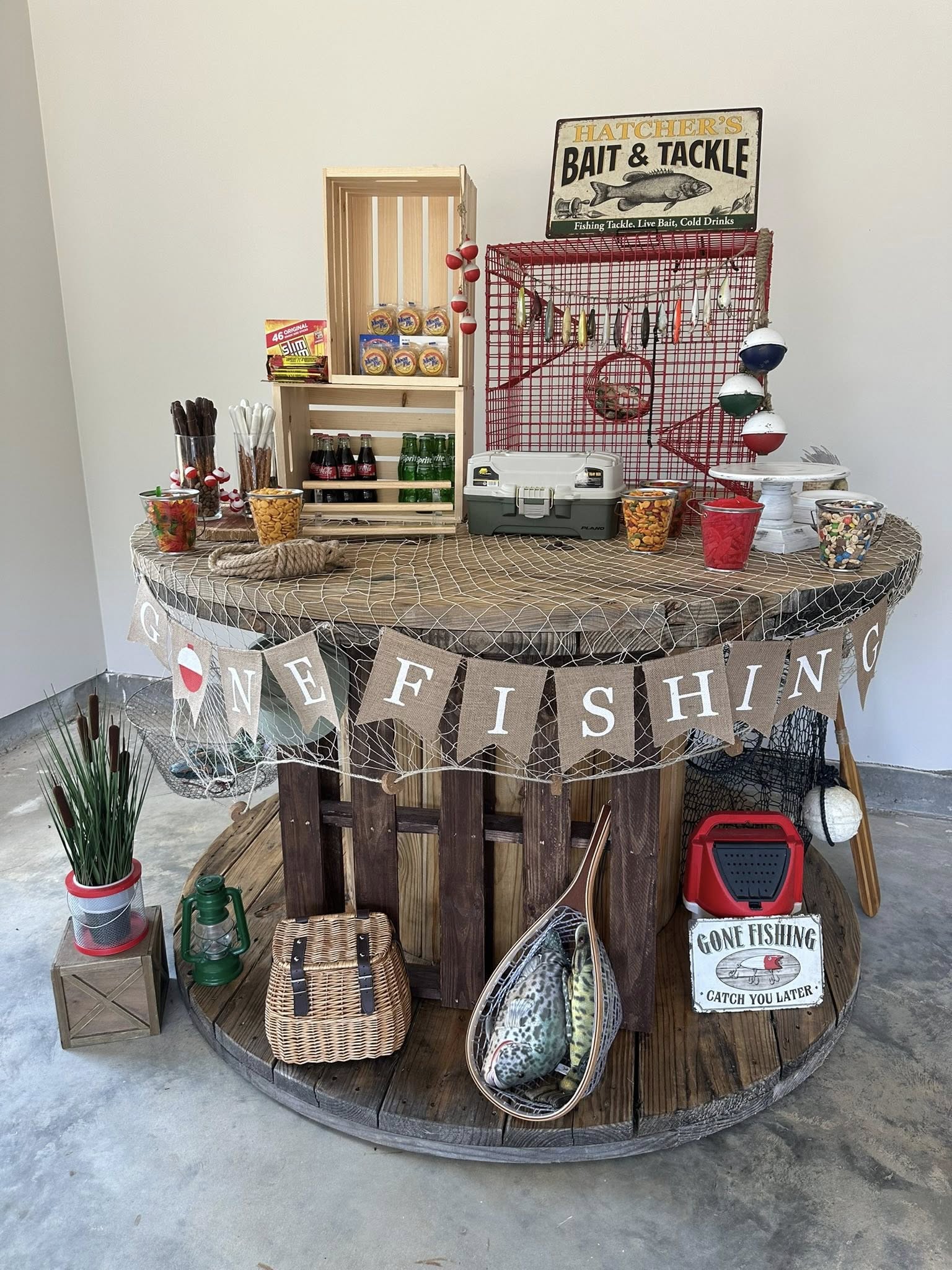 Table styled with a Gone Fishing theme featuring snacks, bait-shop signage, and a wooden spool table.