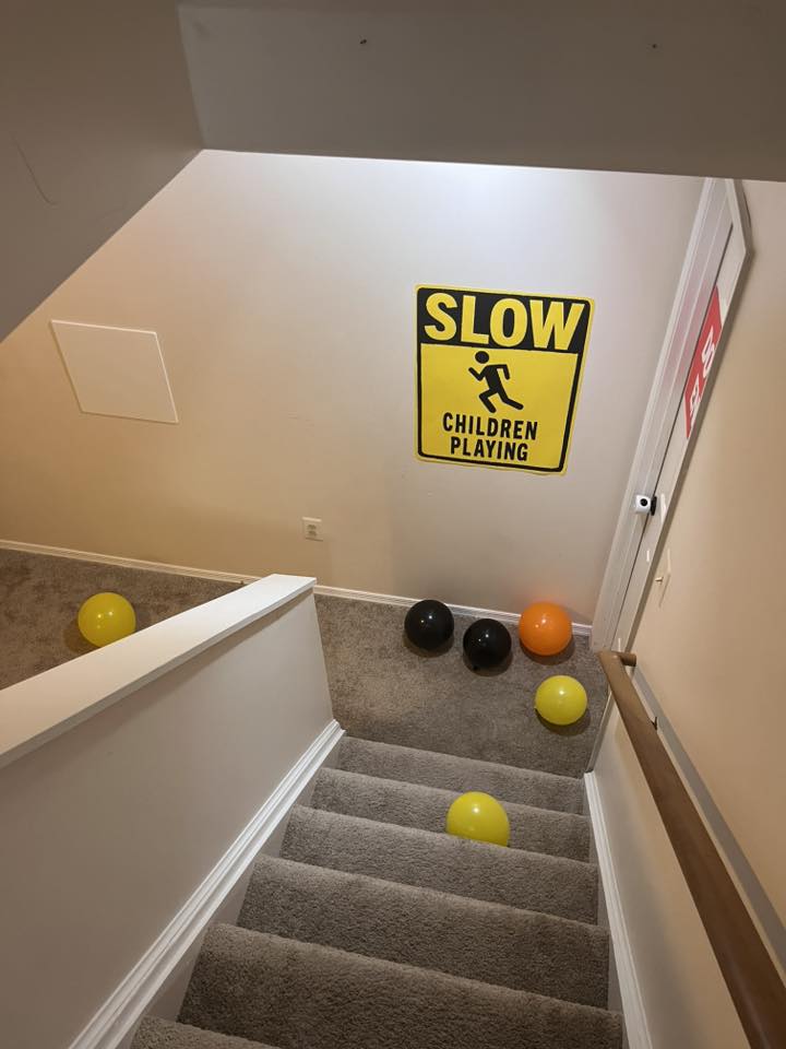 Staircase decorated with colorful balloons and a Slow Children Playing wall sign
