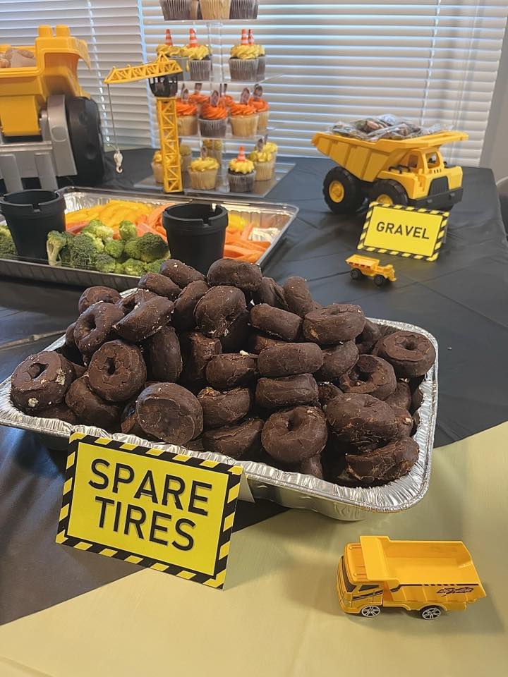 Table with construction-themed party food including chocolate donut spare tires and gravel treats