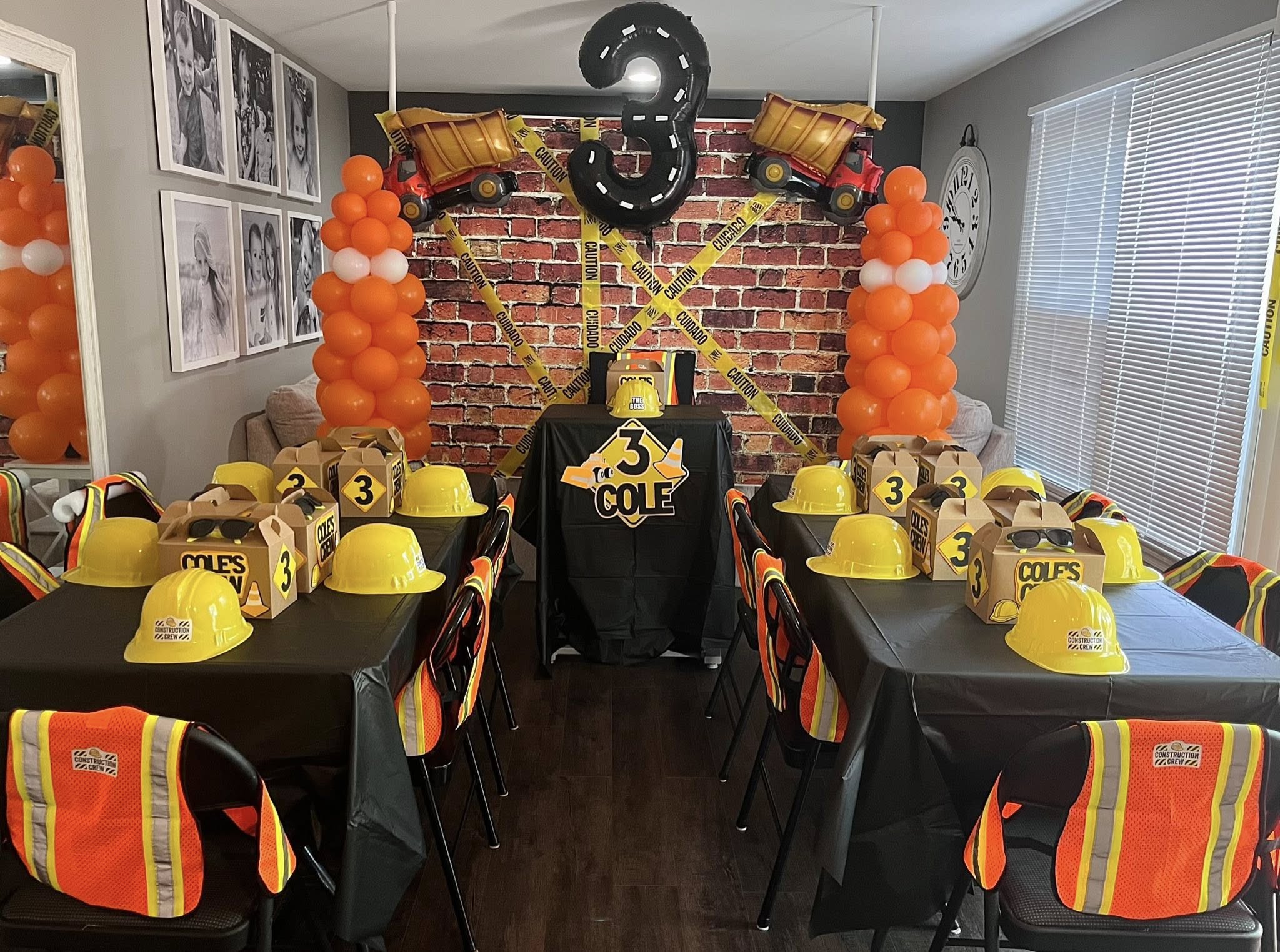 Construction-themed birthday party setup with yellow hard hats, reflective vests, and caution tape decor.