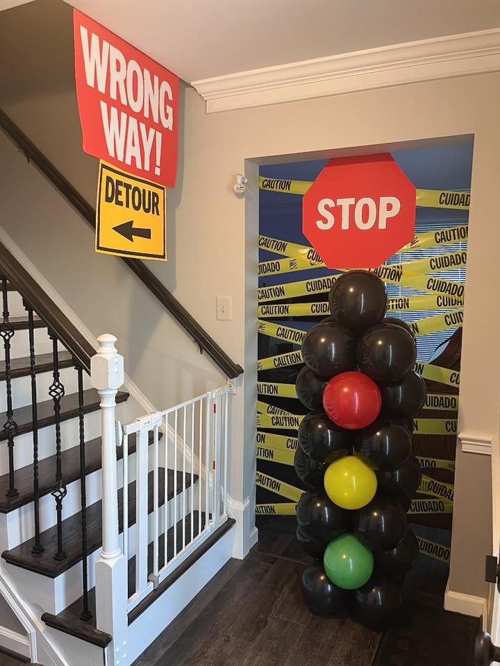Construction-themed party decorations with traffic signs and a balloon traffic light column at a staircase.