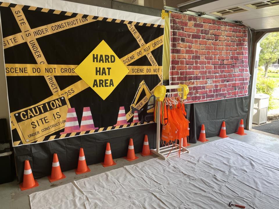 Construction themed party backdrop with Hard Hat Area sign and orange traffic cones