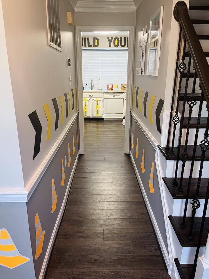 Hallway decorated with orange traffic cone and black arrow wall decals leading to a construction-themed kitchen.