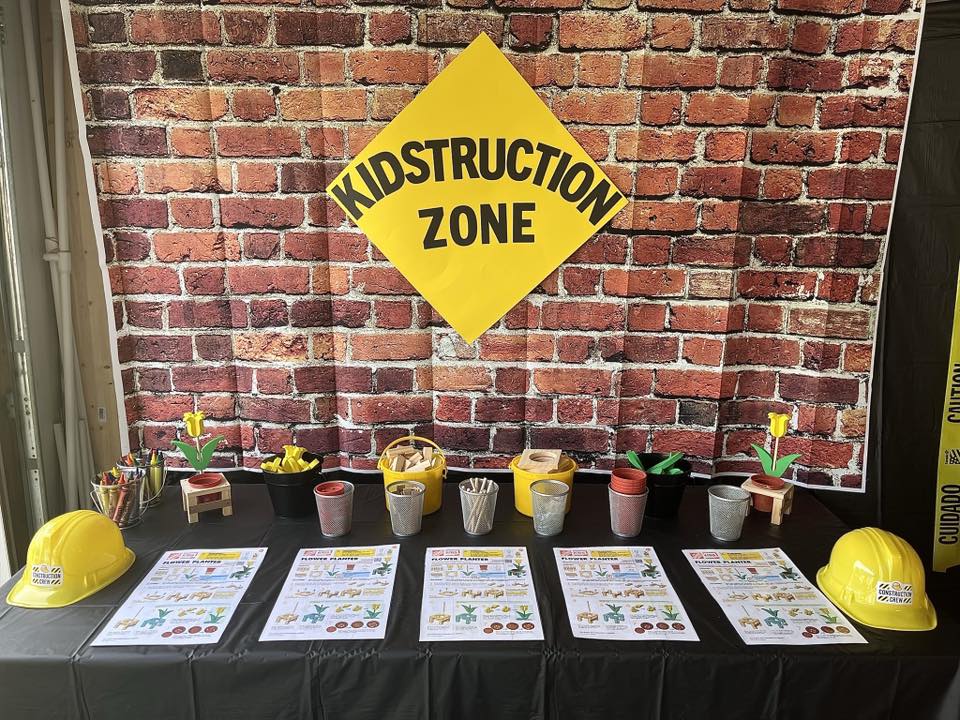 Kidstruction Zone themed party table with activity sheets, yellow construction hats, and craft supplies.