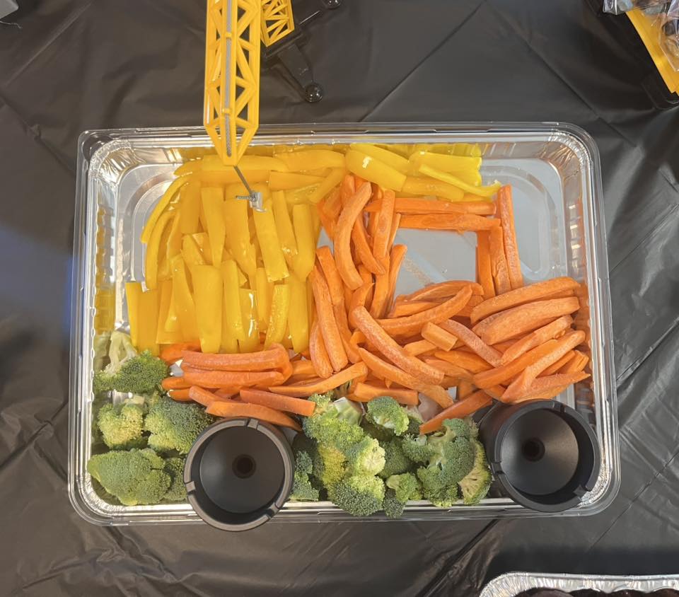 Vegetable tray decorated to look like a construction vehicle with carrot and pepper sticks and broccoli florets.