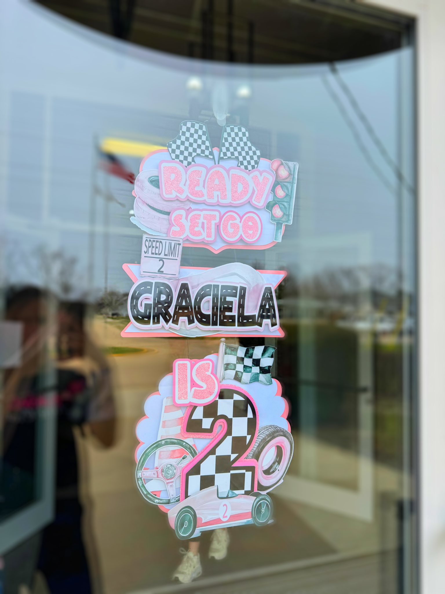 Race car themed Graciela is 2 birthday decoration on glass door