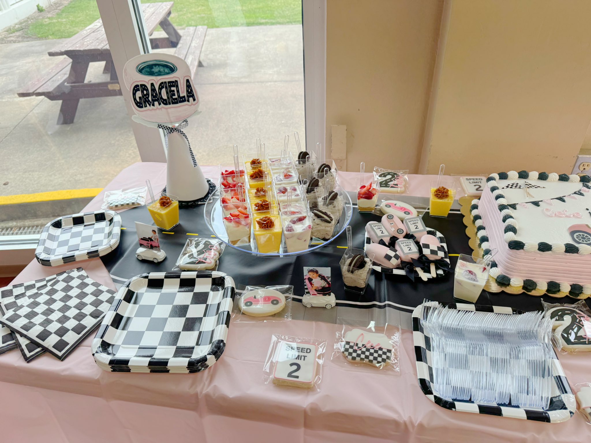 Race car themed party dessert table with checkered plates, speed limit cookies, and custom Graciela table sign.