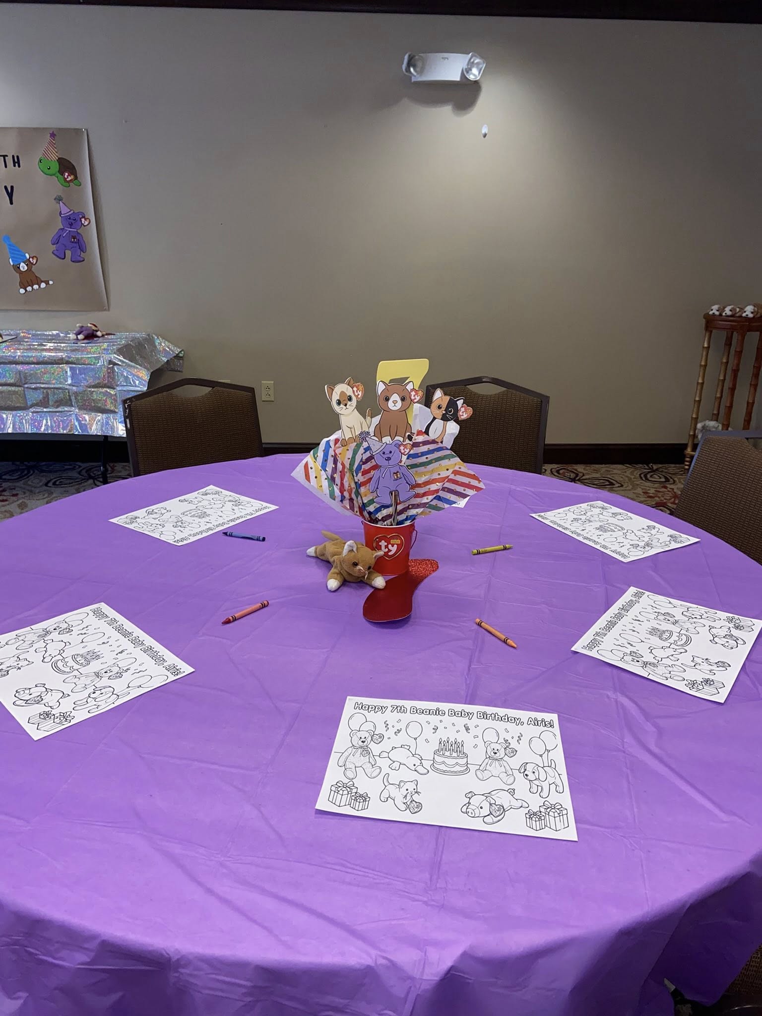 Table set for a Beanie Baby themed 7th birthday party with coloring sheets and a central centerpiece.