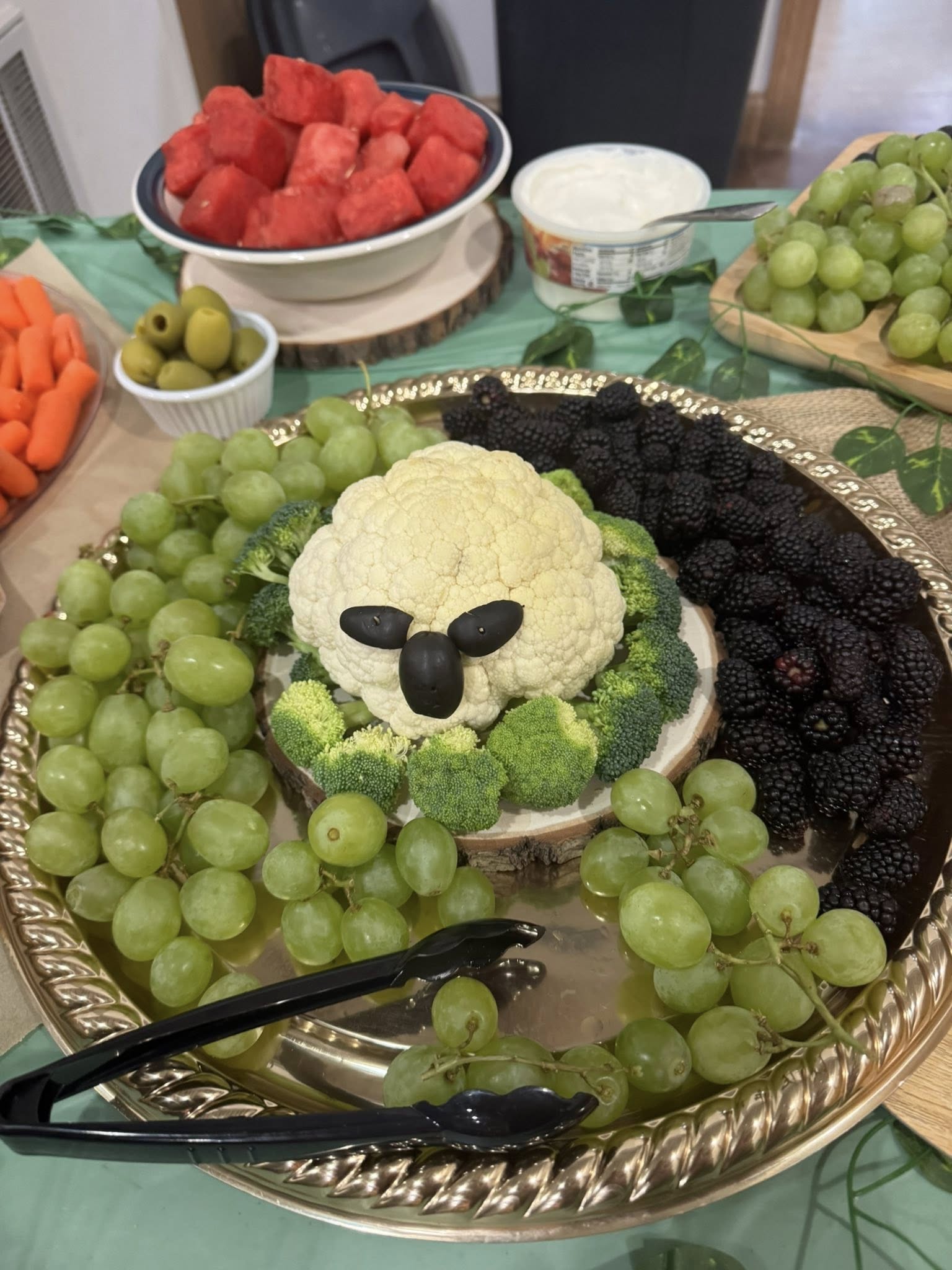 Platter decorated with cauliflower head shaped like a sheep, surrounded by green grapes and blackberries