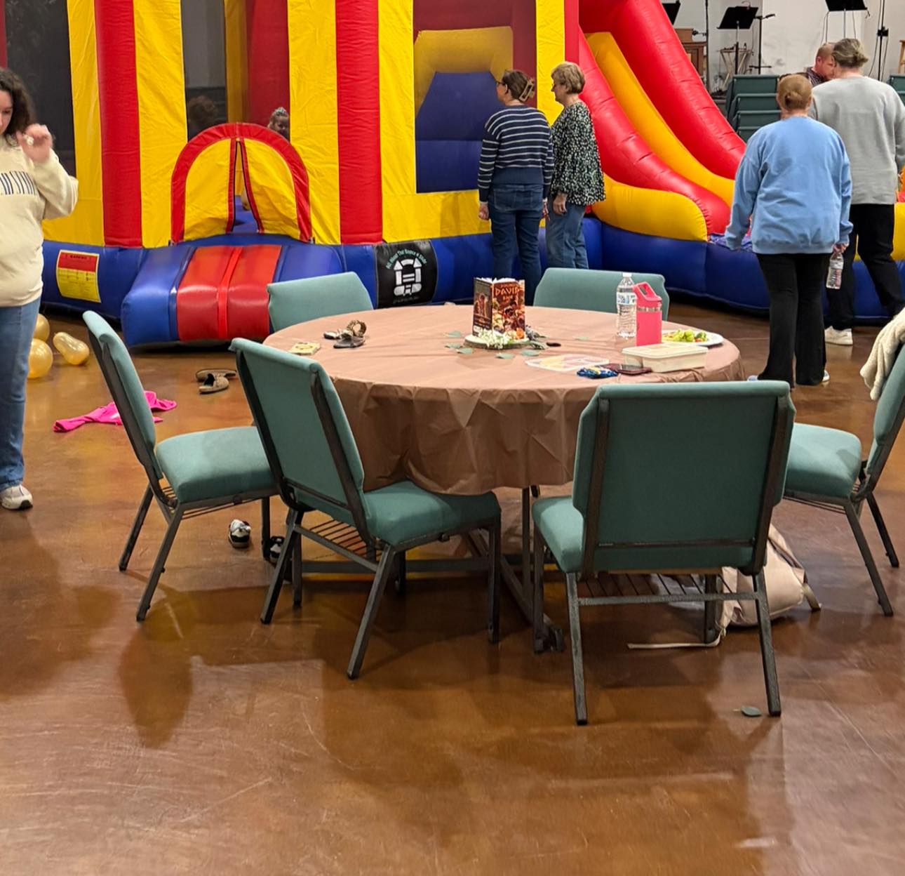 Table with chairs set up in front of an indoor inflatable bouncy castle at a community event.