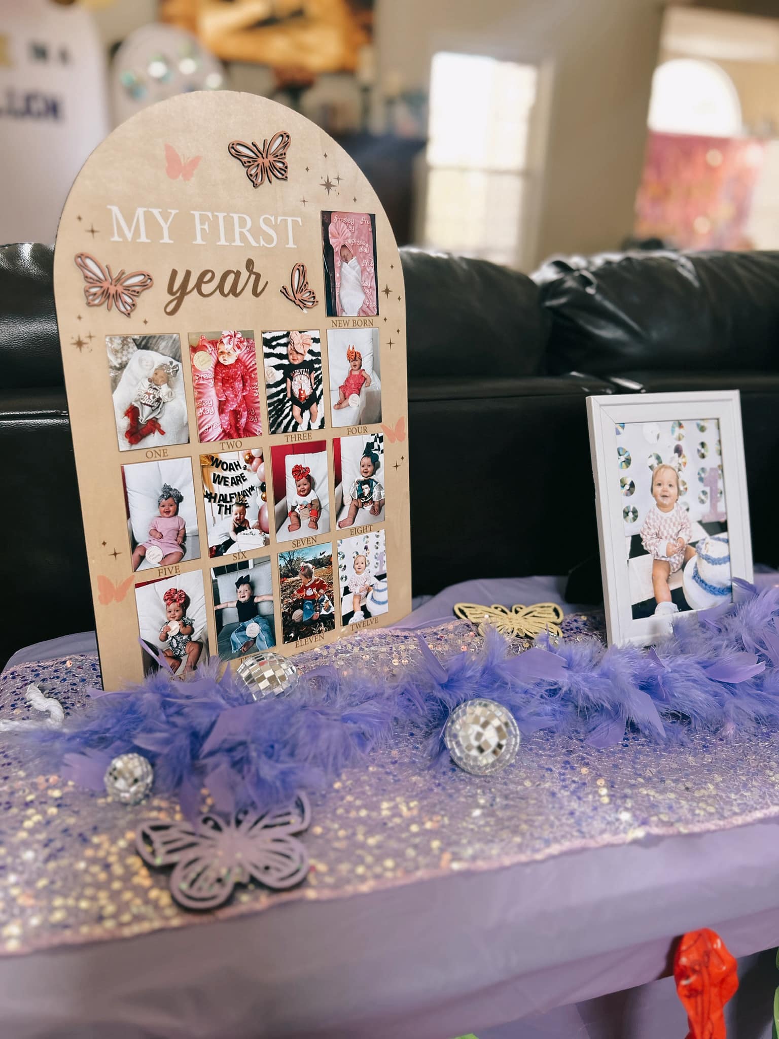 Wooden 'My First Year' photo board documenting a baby's monthly milestones with butterfly decorations.