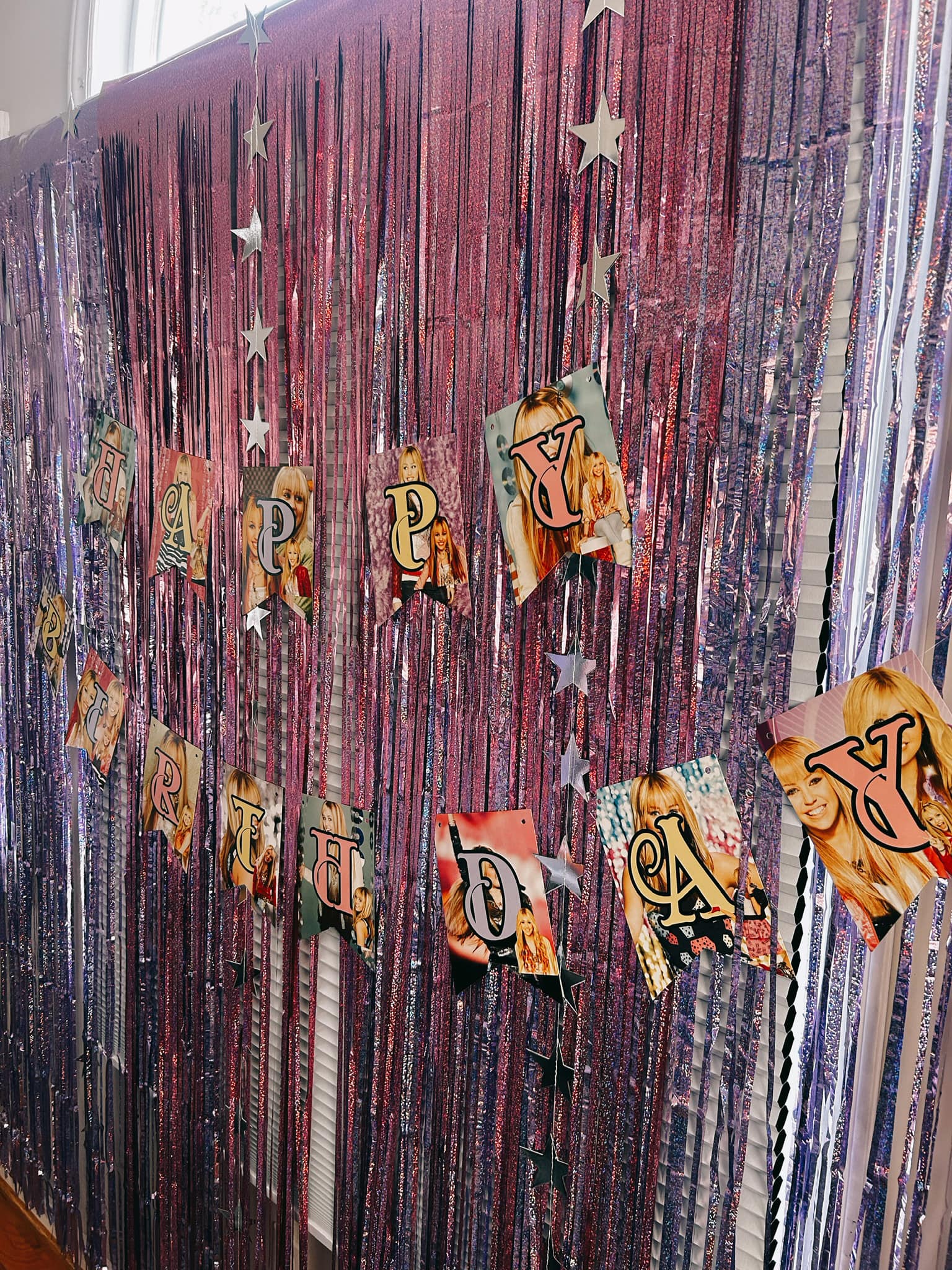Happy Birthday banner featuring photos of Miley Cyrus hanging on a metallic pink fringe curtain backdrop