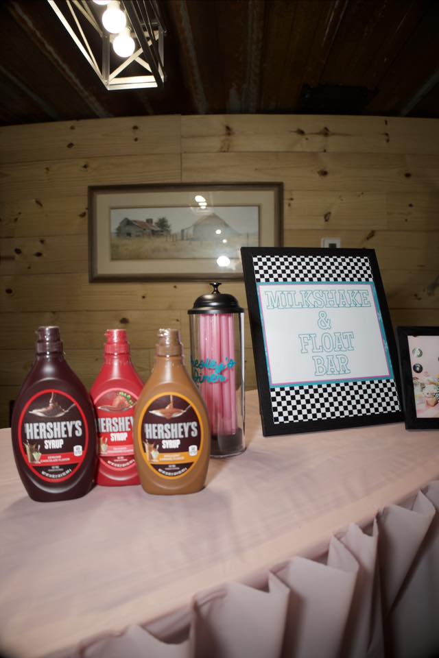 Milkshake and float bar station featuring Hershey's syrups and a decorative sign.