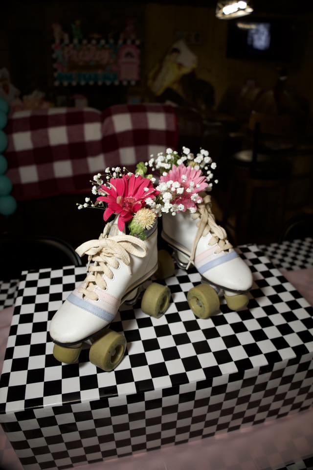 Vintage white roller skates used as a floral centerpiece with pink gerbera daisies and baby's breath.