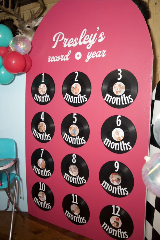 Pink party backdrop for Presley's record year with 12 vinyl record photo slots tracking baby's growth by month.