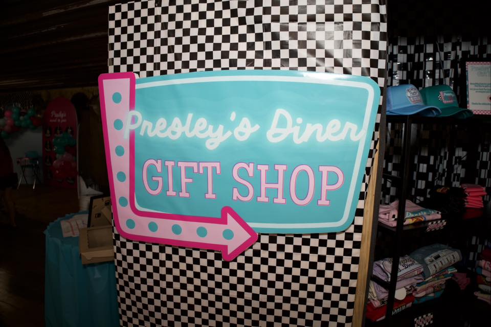 Teal and pink Presley’s Diner Gift Shop sign on a black and white checkerboard background