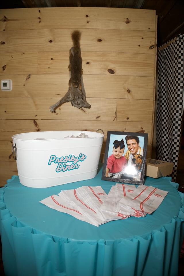 Presley's Diner branded beverage tub with table linens and framed photo on a blue tablecloth