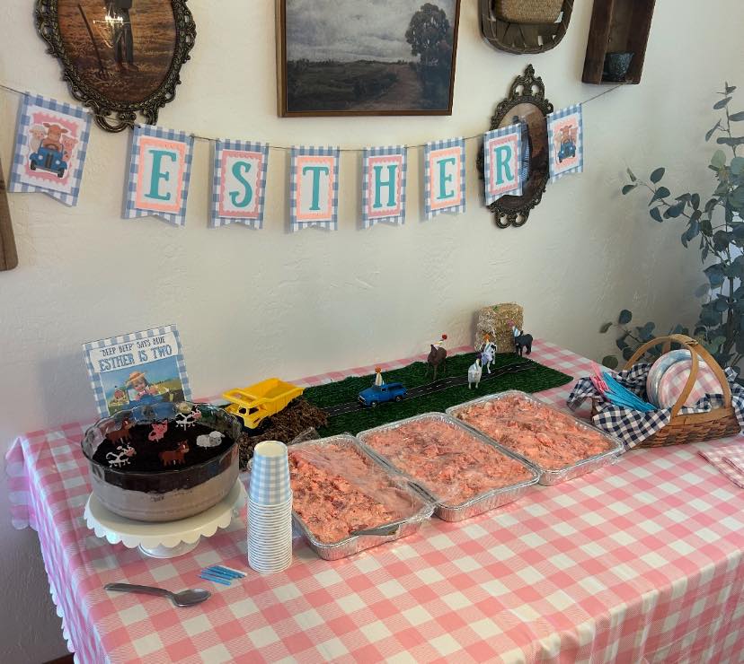 Table set for a farmhouse or truck themed second birthday party with an Esther name banner.
