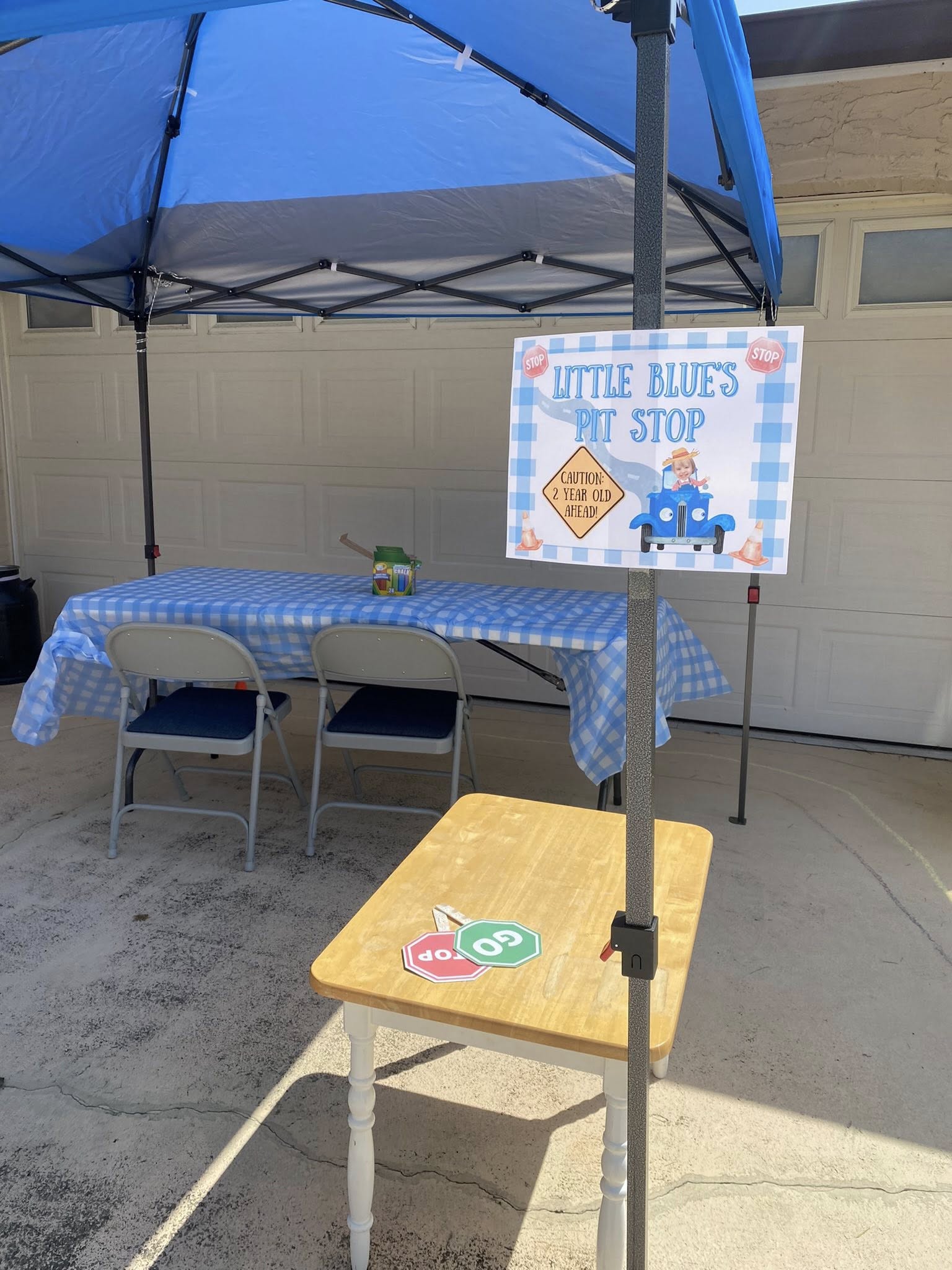 Table party display with blue checkered tablecloth and signage for a Little Blue's Pit Stop 2nd birthday party.