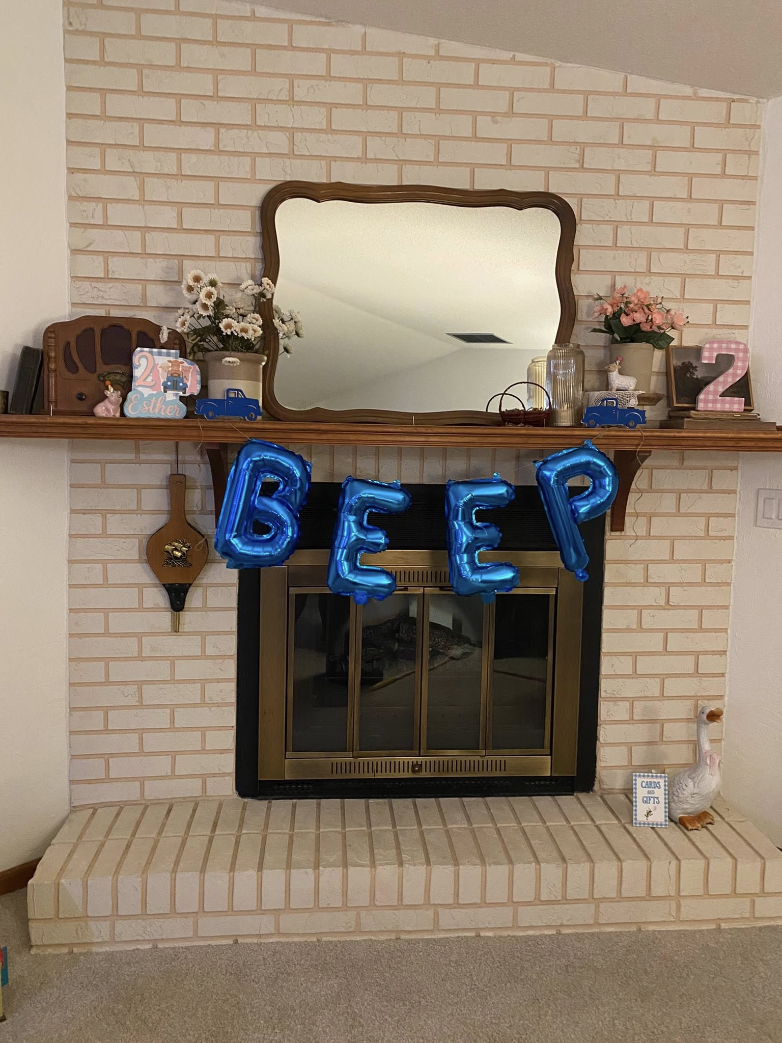 Mantelpiece decorated for a second birthday with blue 'BEEP' foil balloons.