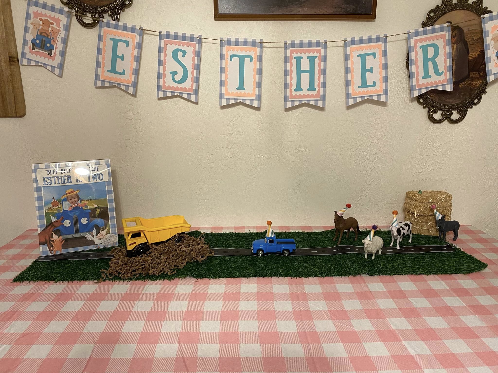 Table display featuring a farm-themed two-year-old birthday party setup with a banner spelling Esther.
