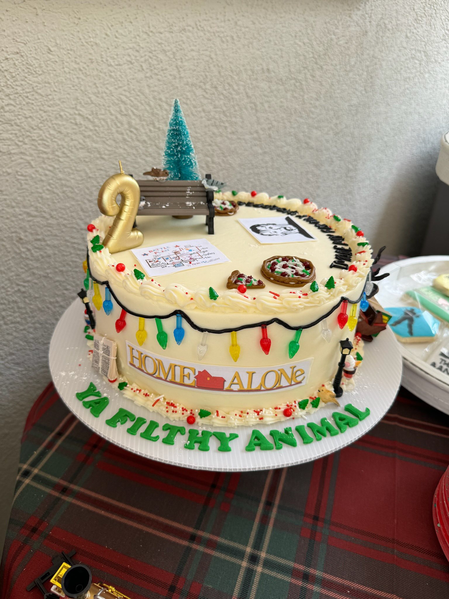 Home Alone themed birthday cake with colorful lights, a pizza, a battle plan illustration, and the text Ya Filthy Animal.