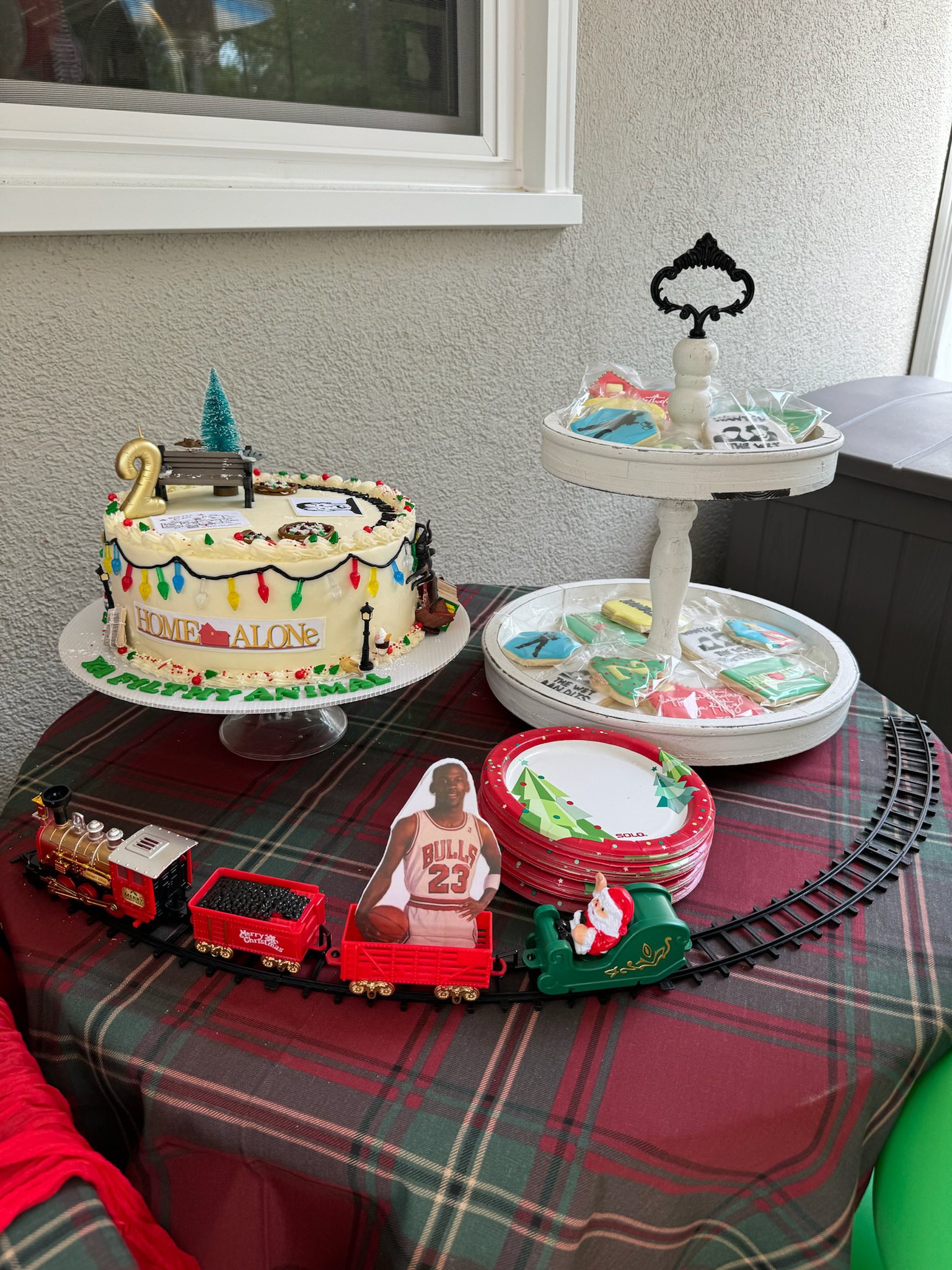 Home Alone themed birthday cake with a toy train carrying a Michael Jordan cutout on a plaid tablecloth