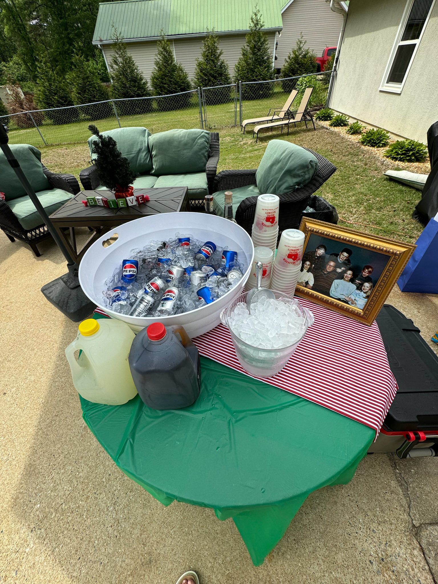 Table with a beverage station featuring Pepsi cans in an ice bucket, jugs of drinks, and a framed McCallister family portrait from Home Alone.