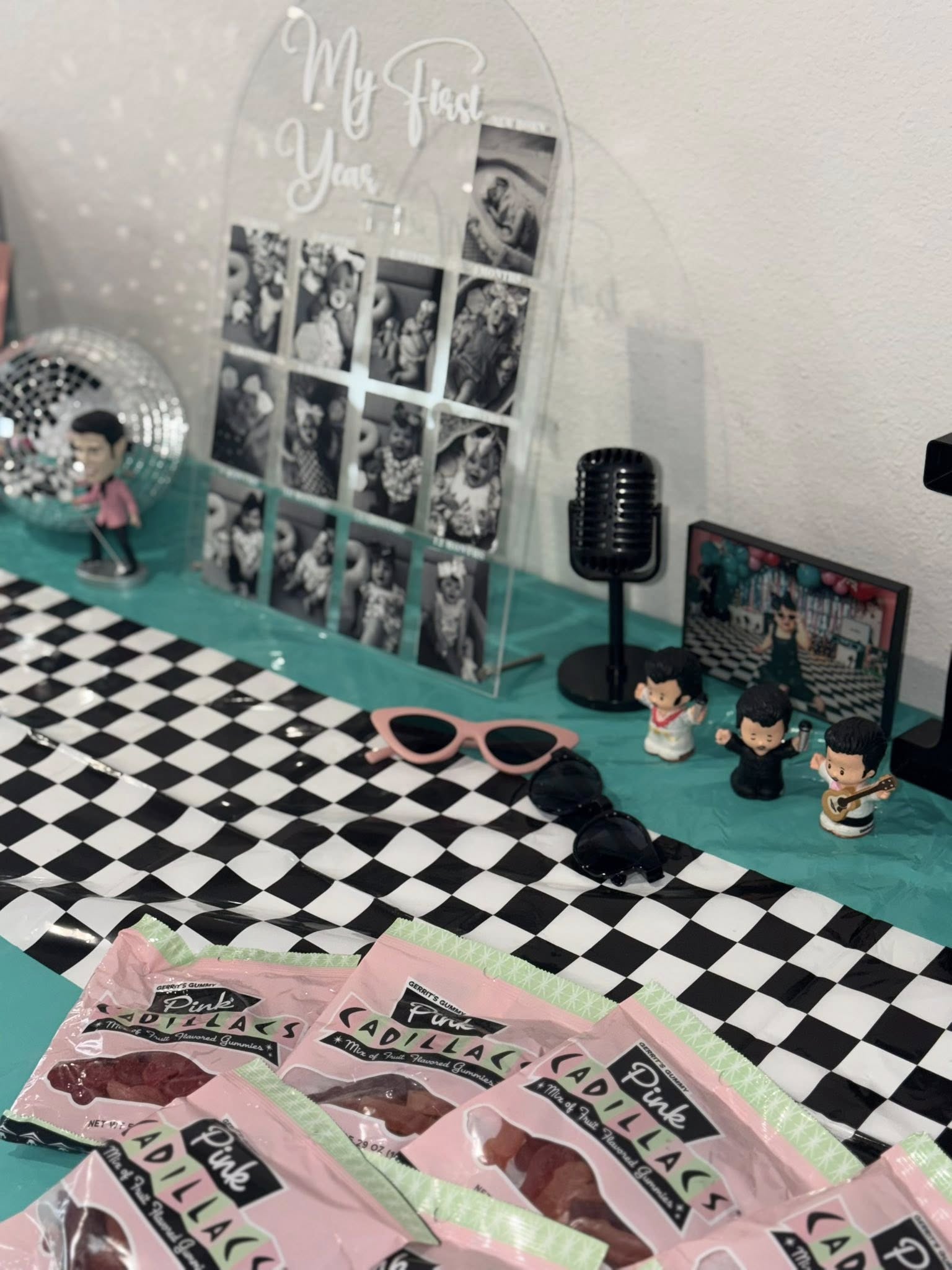 50s rock and roll themed birthday table display with Pink Cadillac gummy candy, Elvis figures, and photo board.