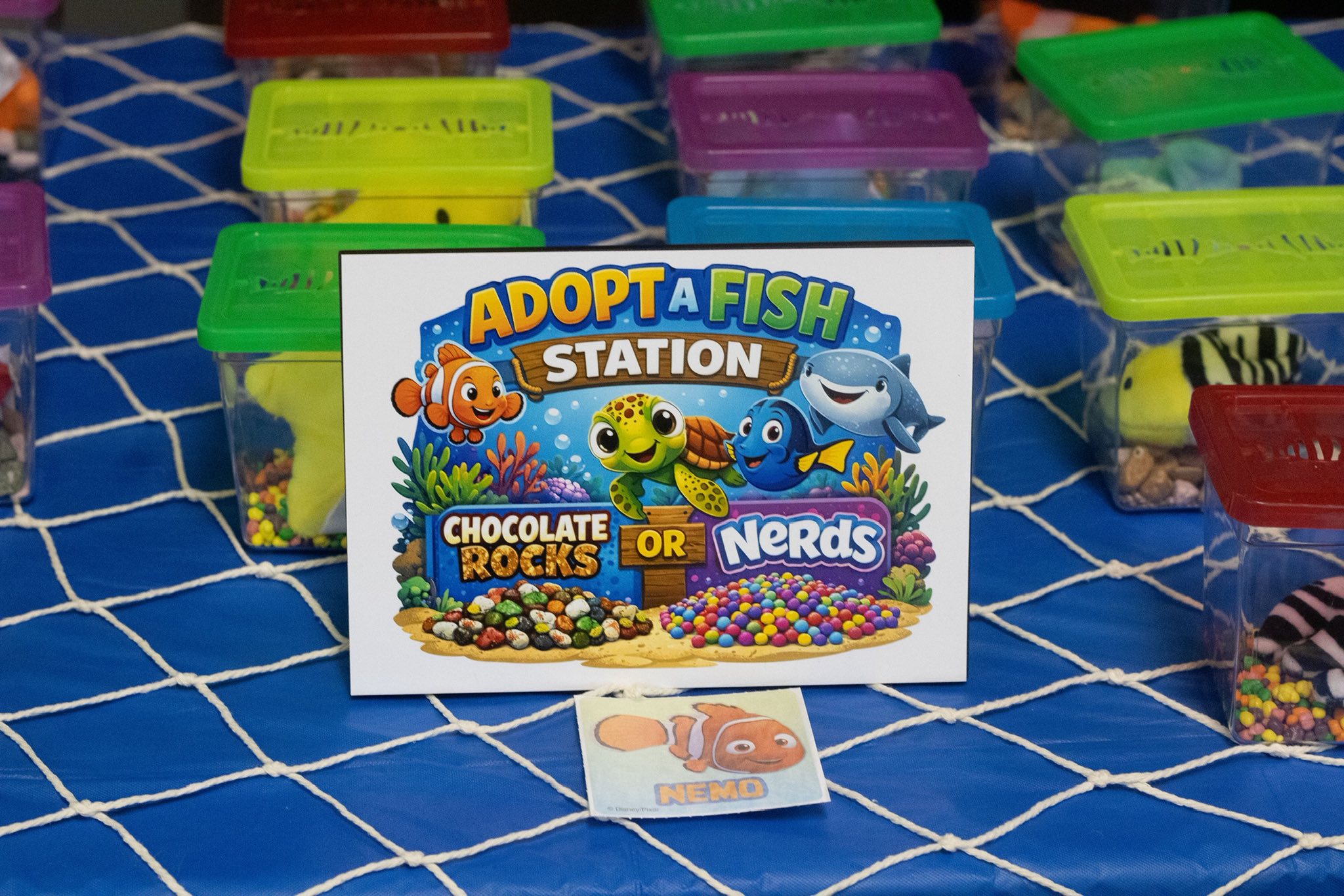 Adopt a Fish station sign featuring Finding Nemo characters with options for chocolate rocks or Nerds candy.