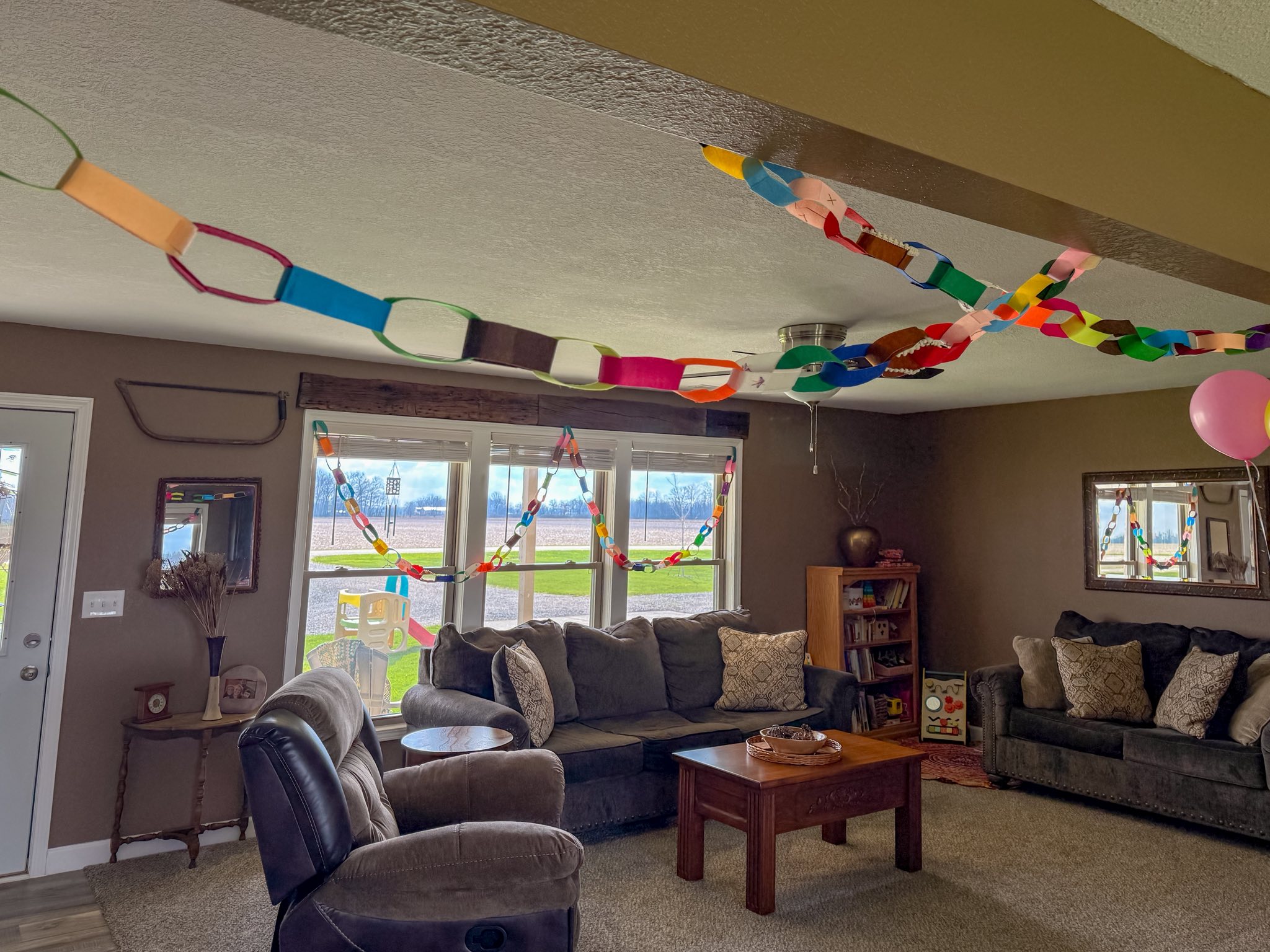 Well decorated living room with handmade paper chains hanging from the ceiling and a pink balloon.