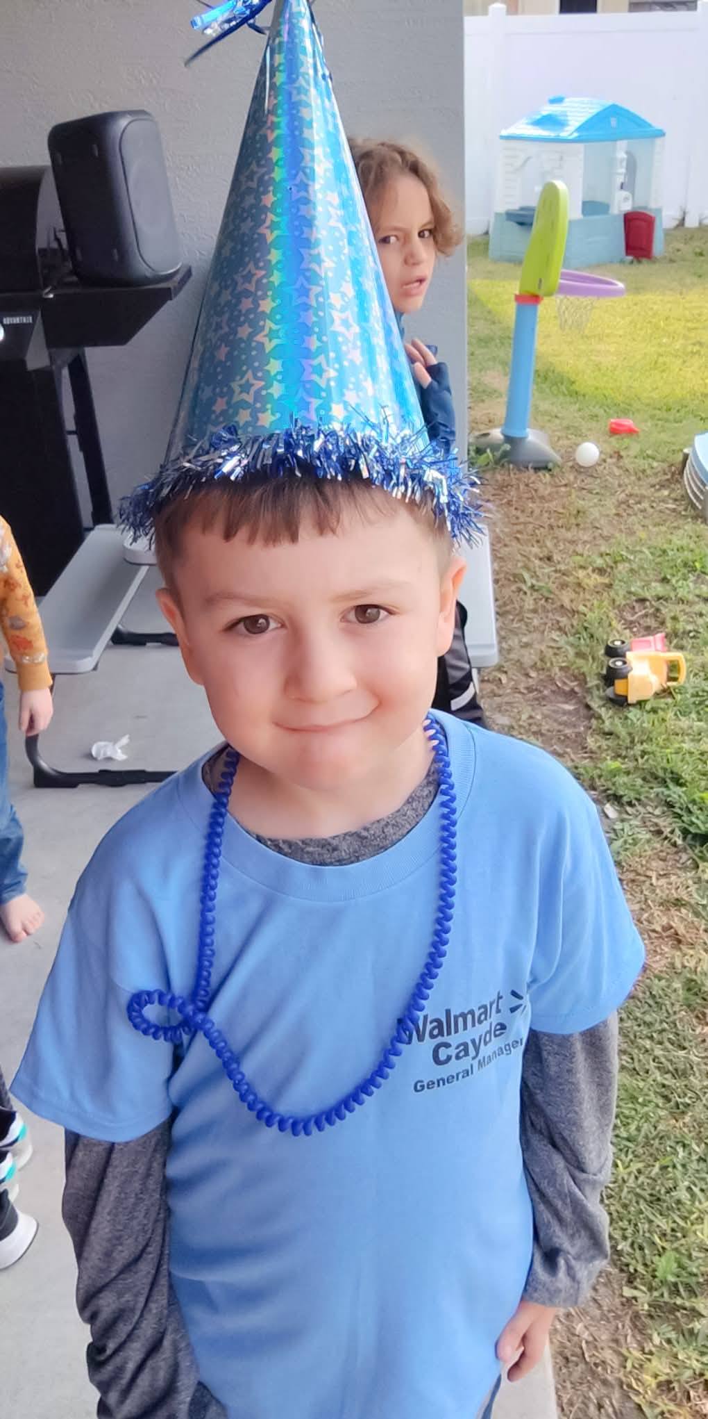 Young boy wearing a blue party hat and a blue Walmart branded t-shirt.